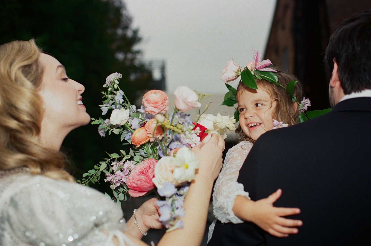 A sweet candid moment captured at a wedding with soft pink roses and white floral bouquets in focus.