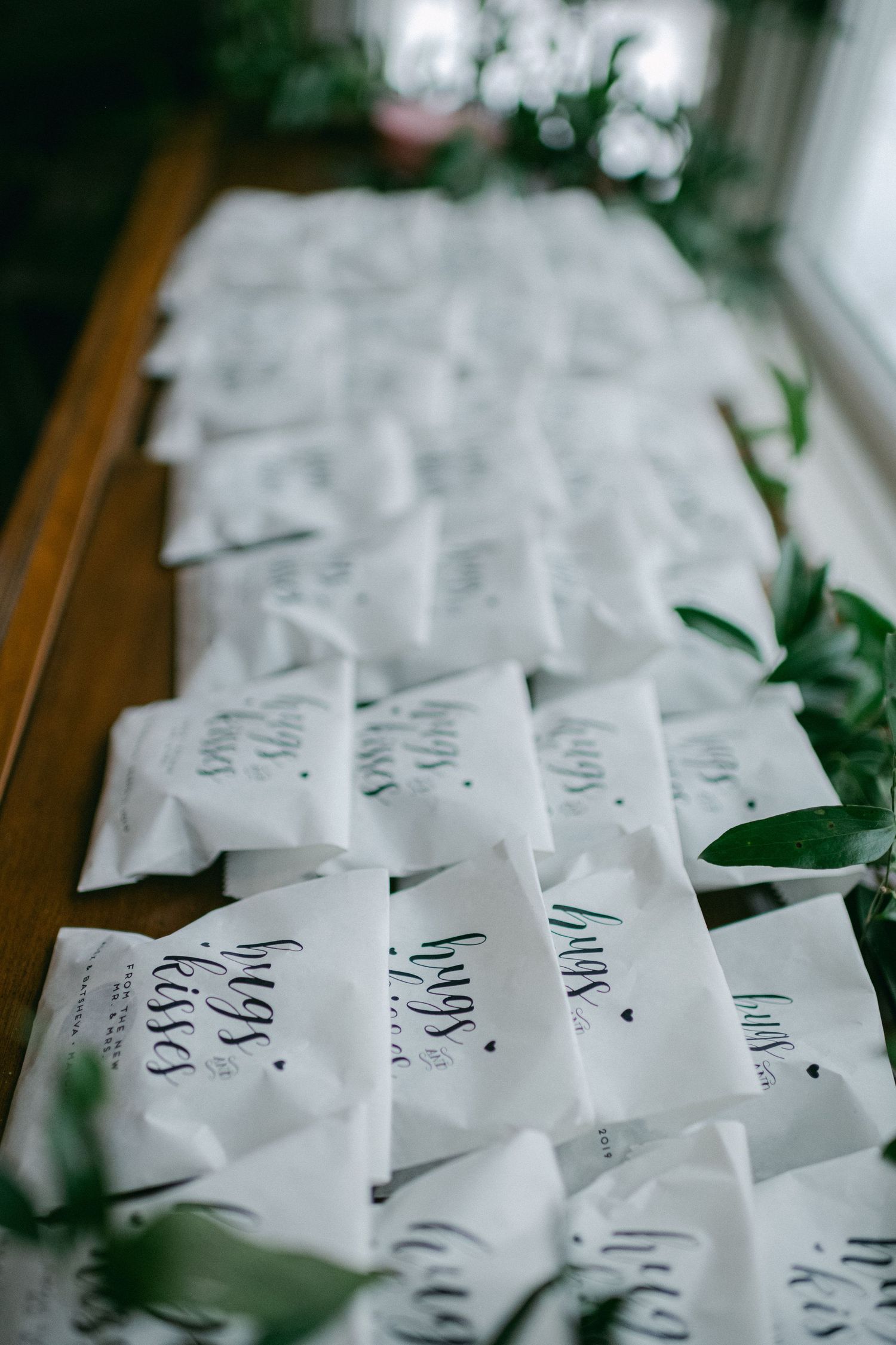 Rows of beautifully arranged wedding place cards with greenery accents.