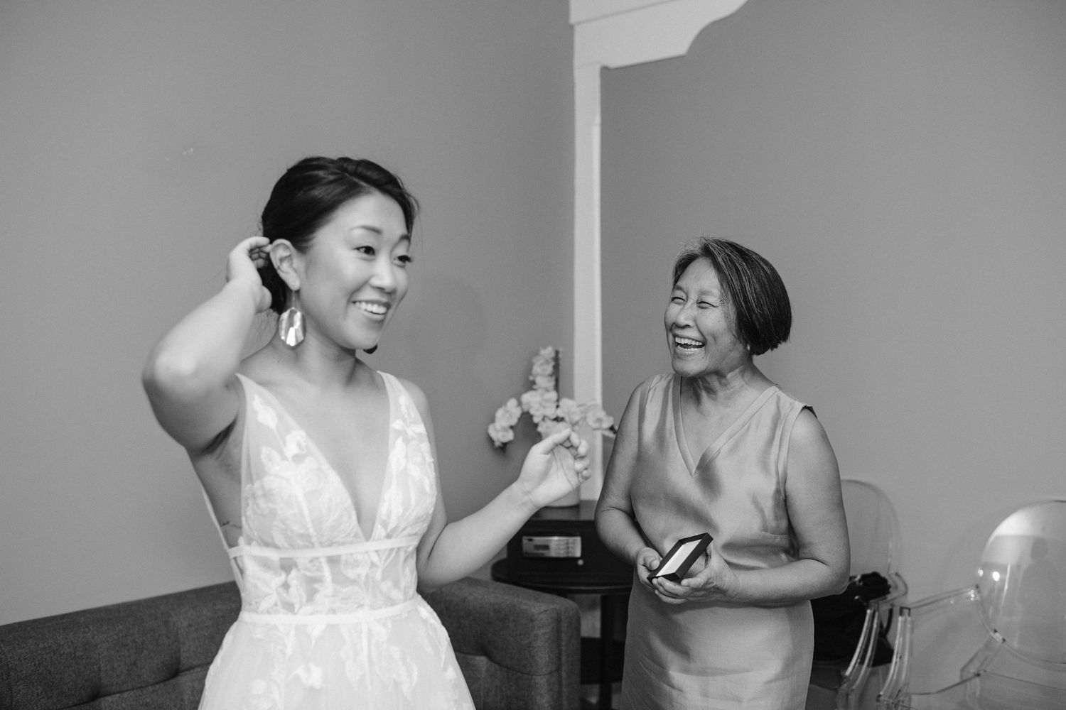 mother smiles and bride checks her hair in the mirror