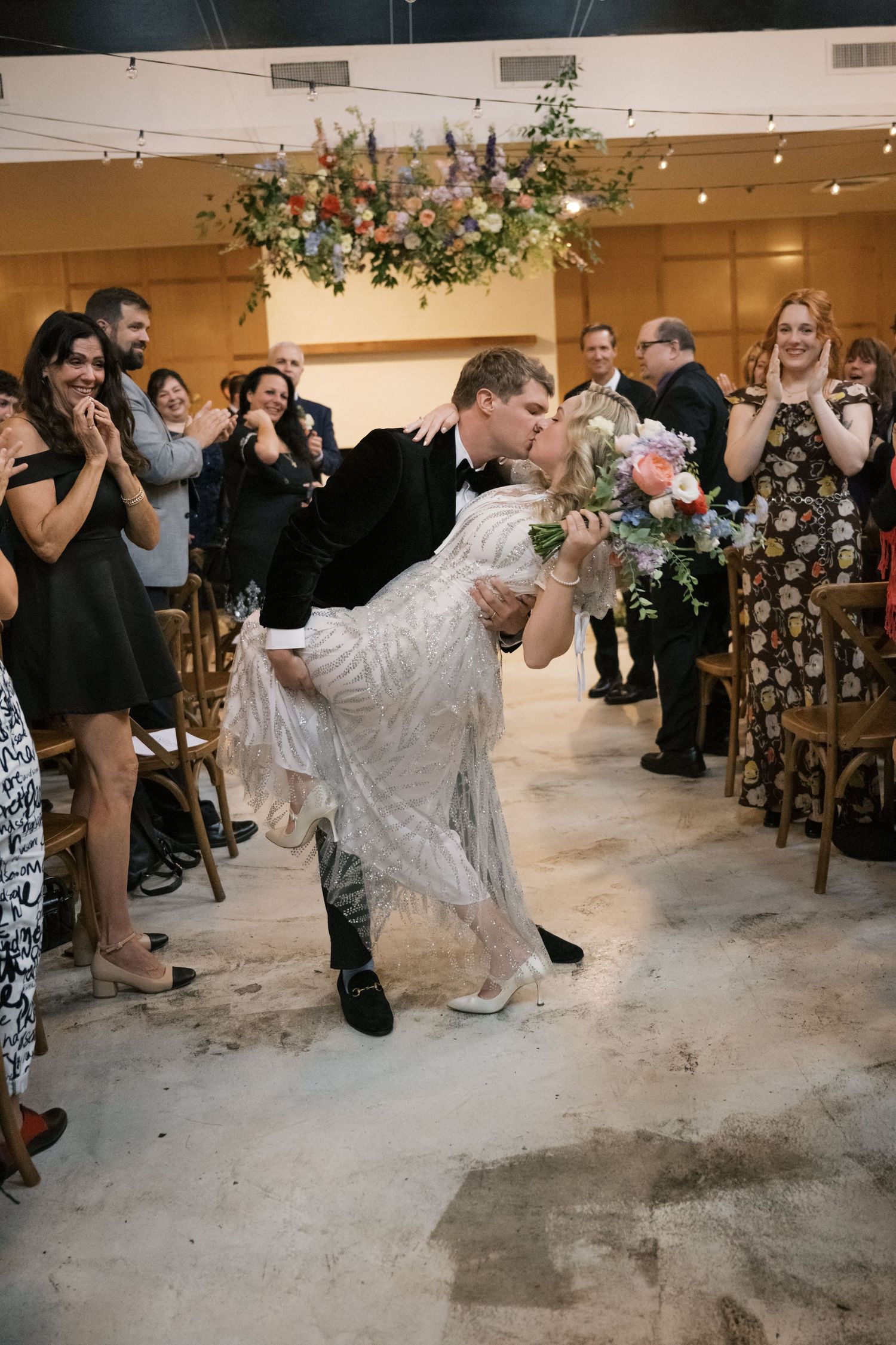 A romantic dip during a wedding first dance while guests watch and cheer.