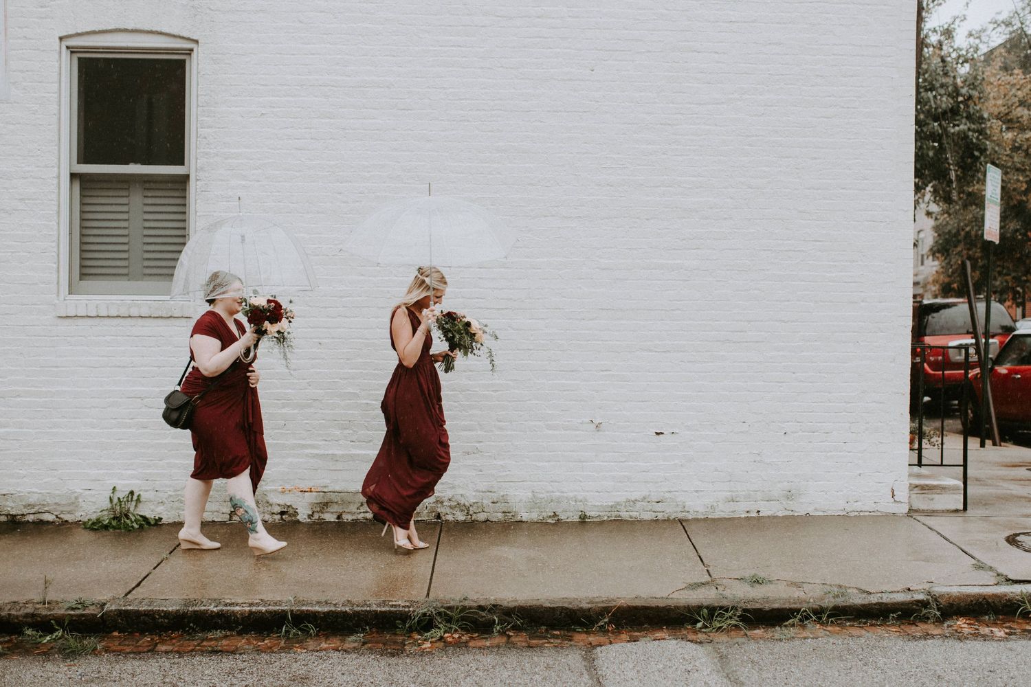 Couple walking along a white brick building wall in casual attire.
