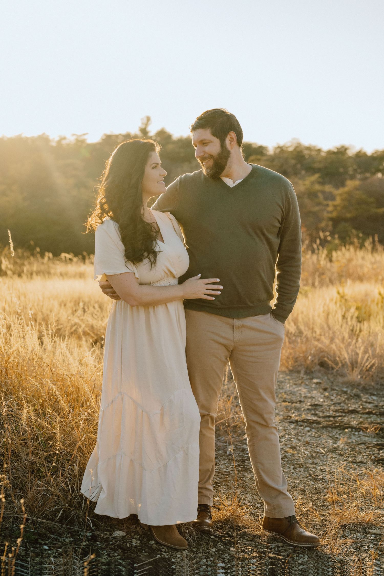 Couple shares intimate moment in golden sunset field.