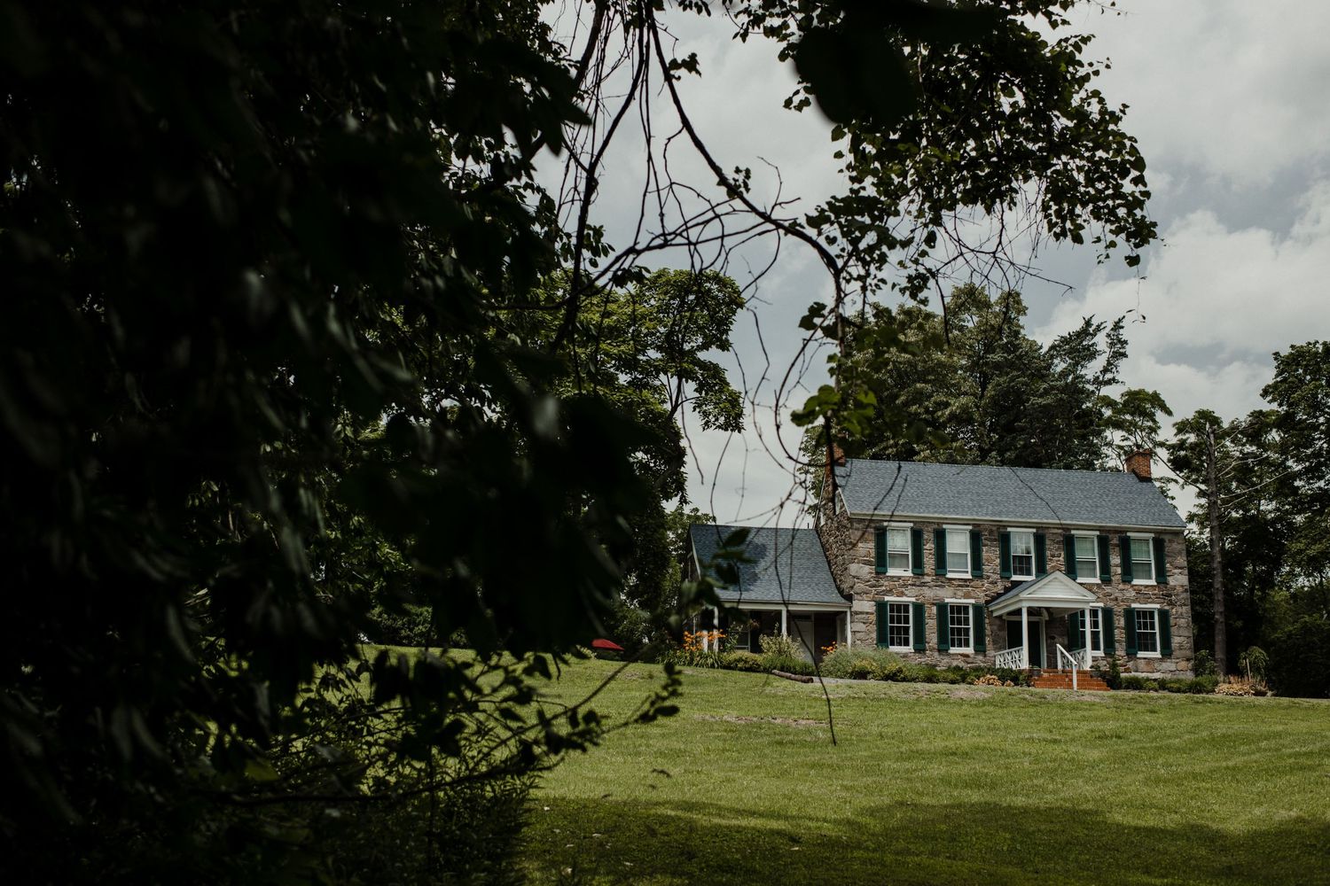 A stately colonial-style house with white columns sits on a sprawling green lawn.