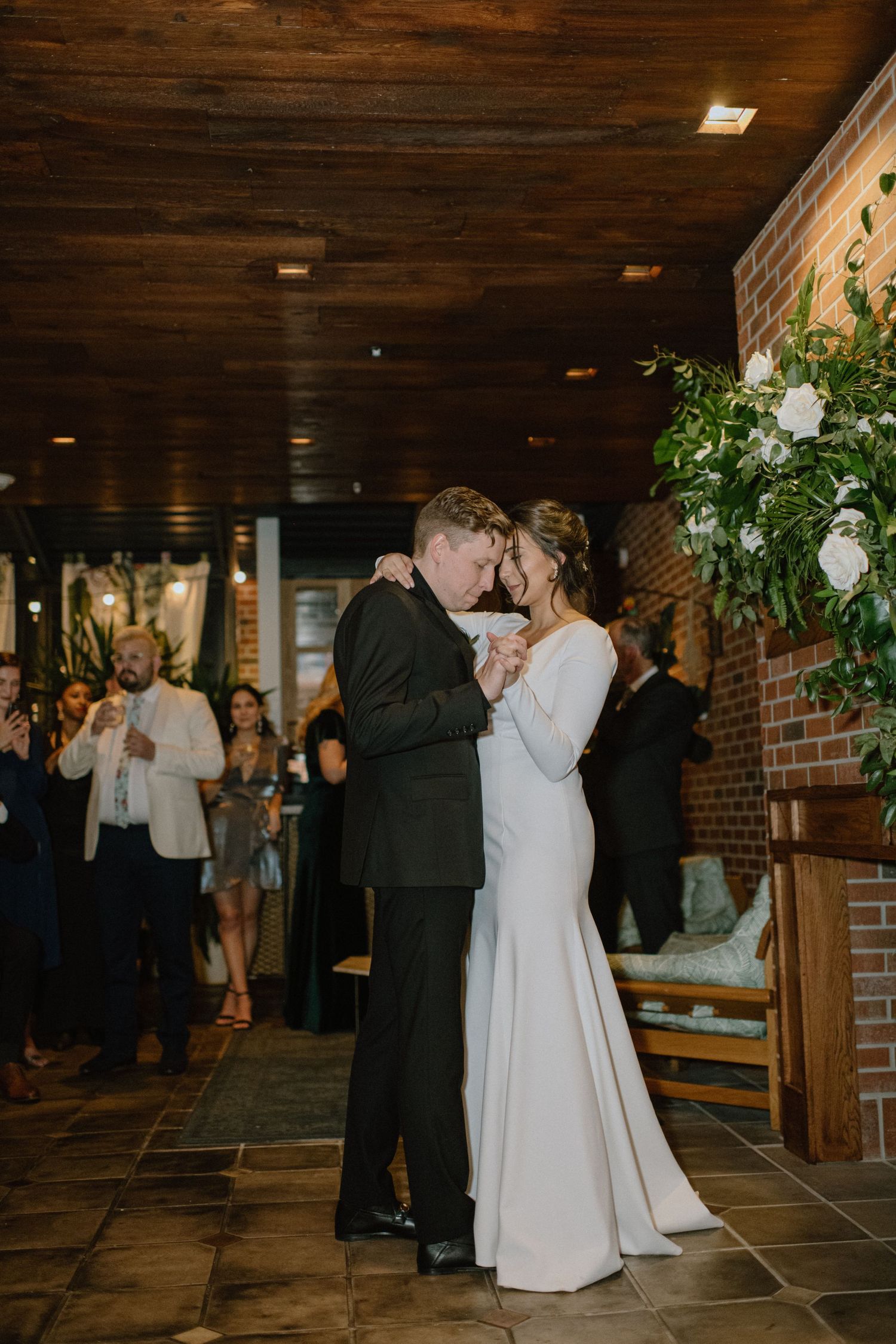 A first dance moment in an elegant venue with exposed brick walls and wooden ceiling.