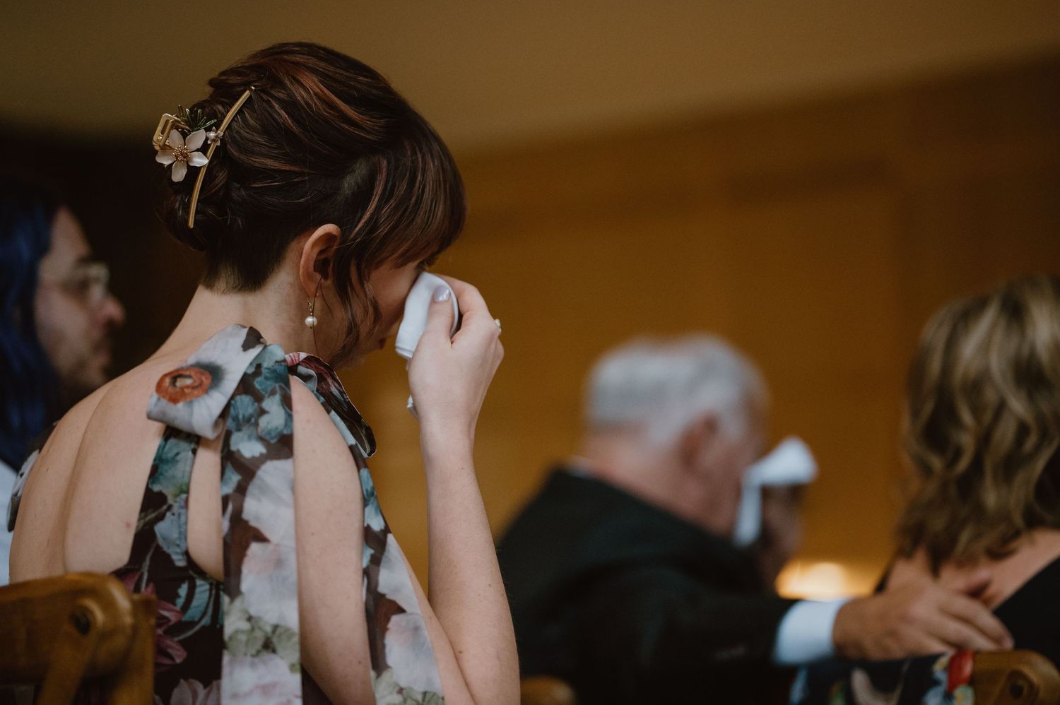 A guest wipes tears during an emotional moment at a wedding reception.