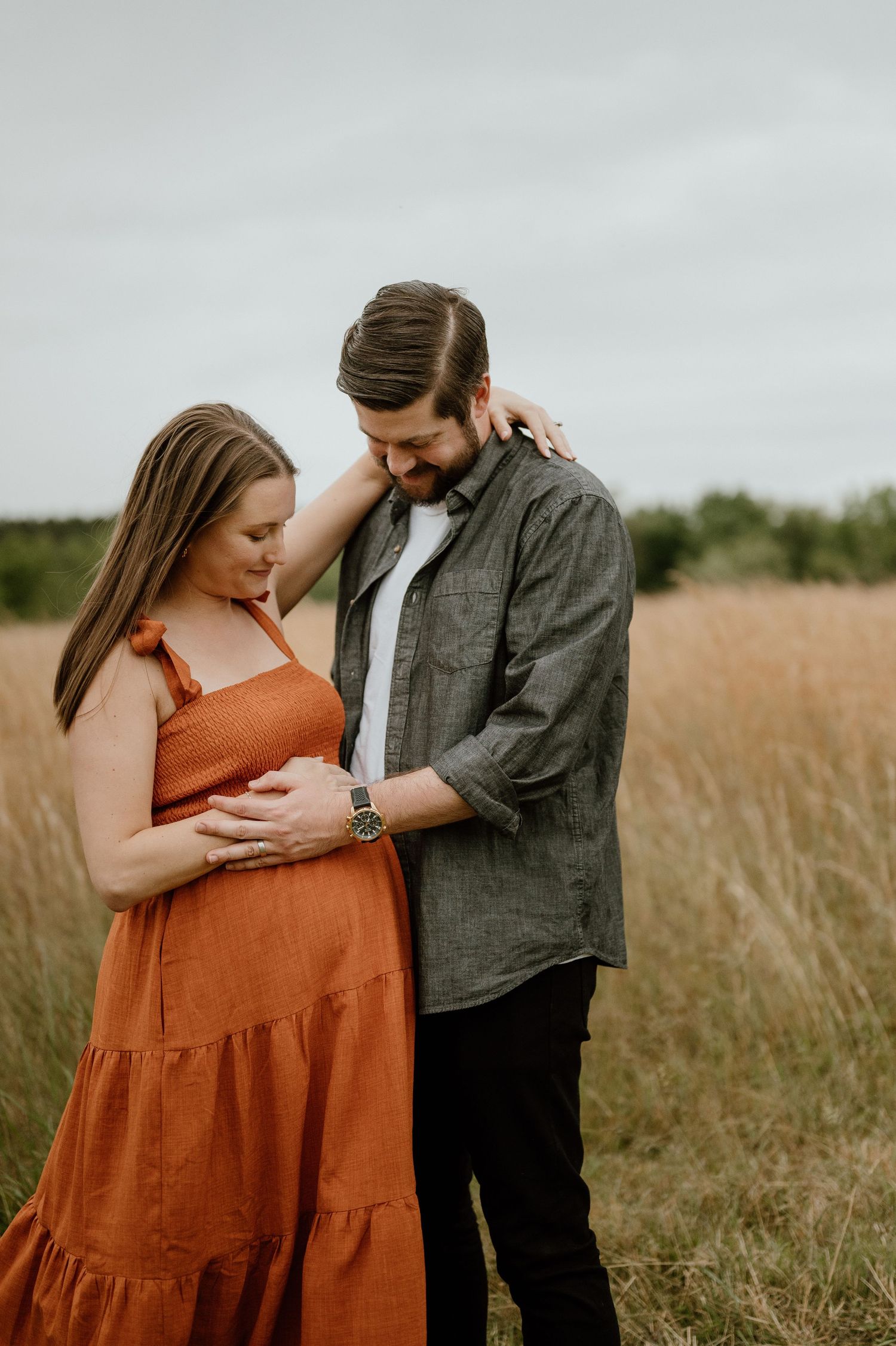 Intimate maternity moment between couple in rustic outdoor setting.