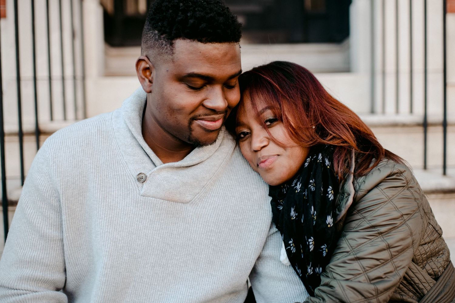 A couple shares a tender moment while sitting on brownstone steps.