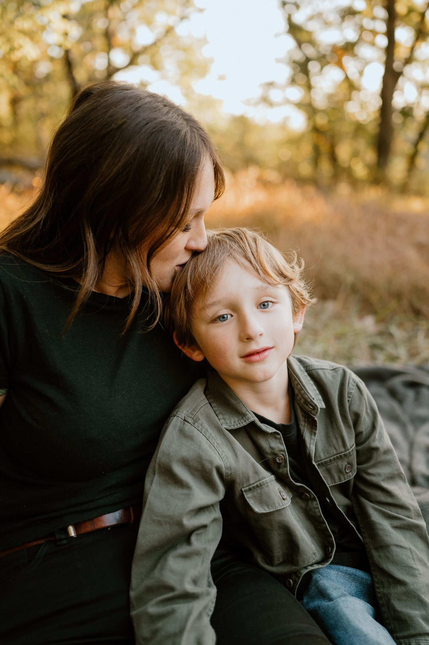 A gentle moment captured in golden hour lighting while sitting on a blanket outdoors.