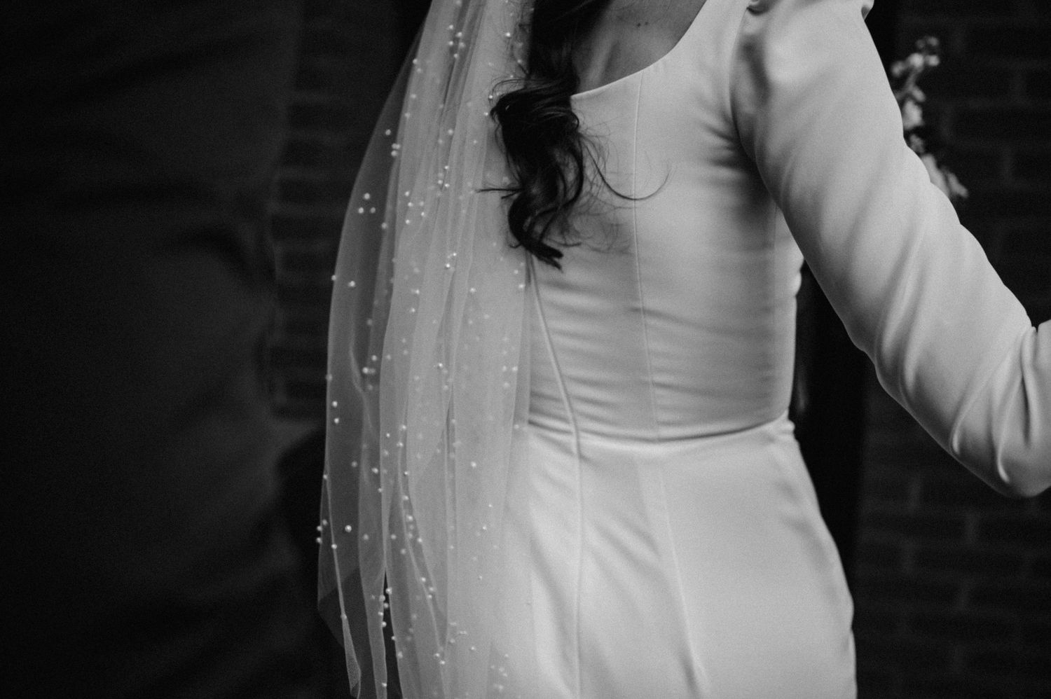 Close-up detail of elegant white wedding dress and veil with pearl accents.
