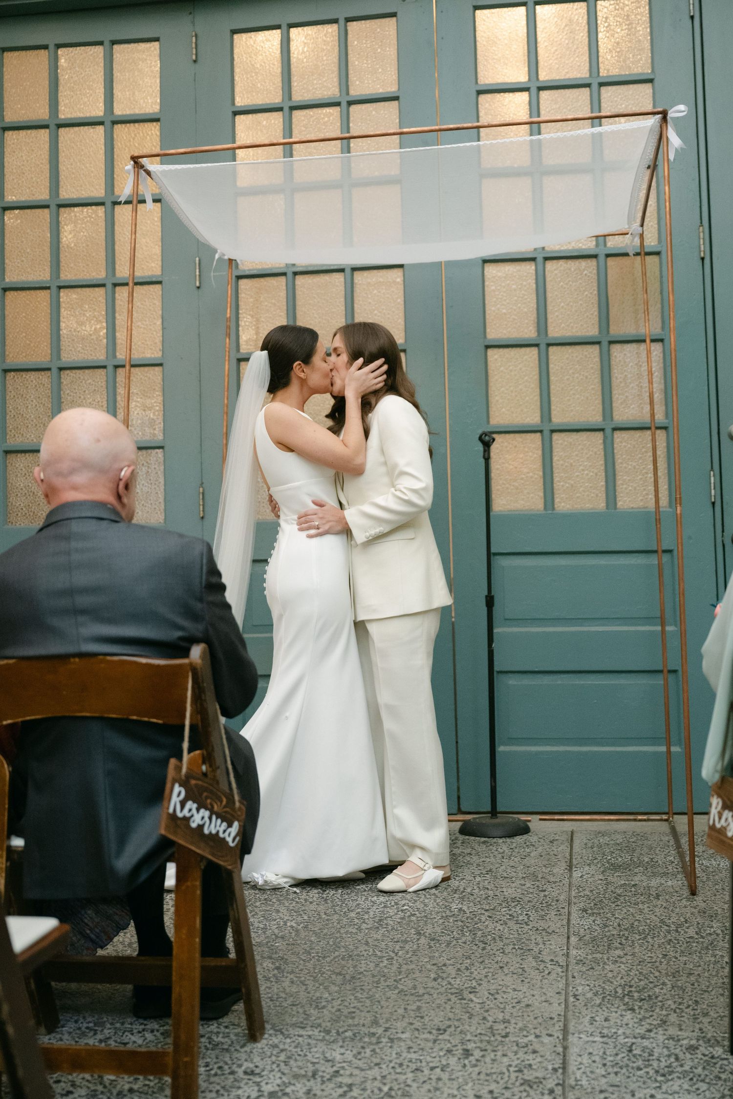 A series of wedding photos showing a romantic moment between a couple against green doors in an outdoor setting.