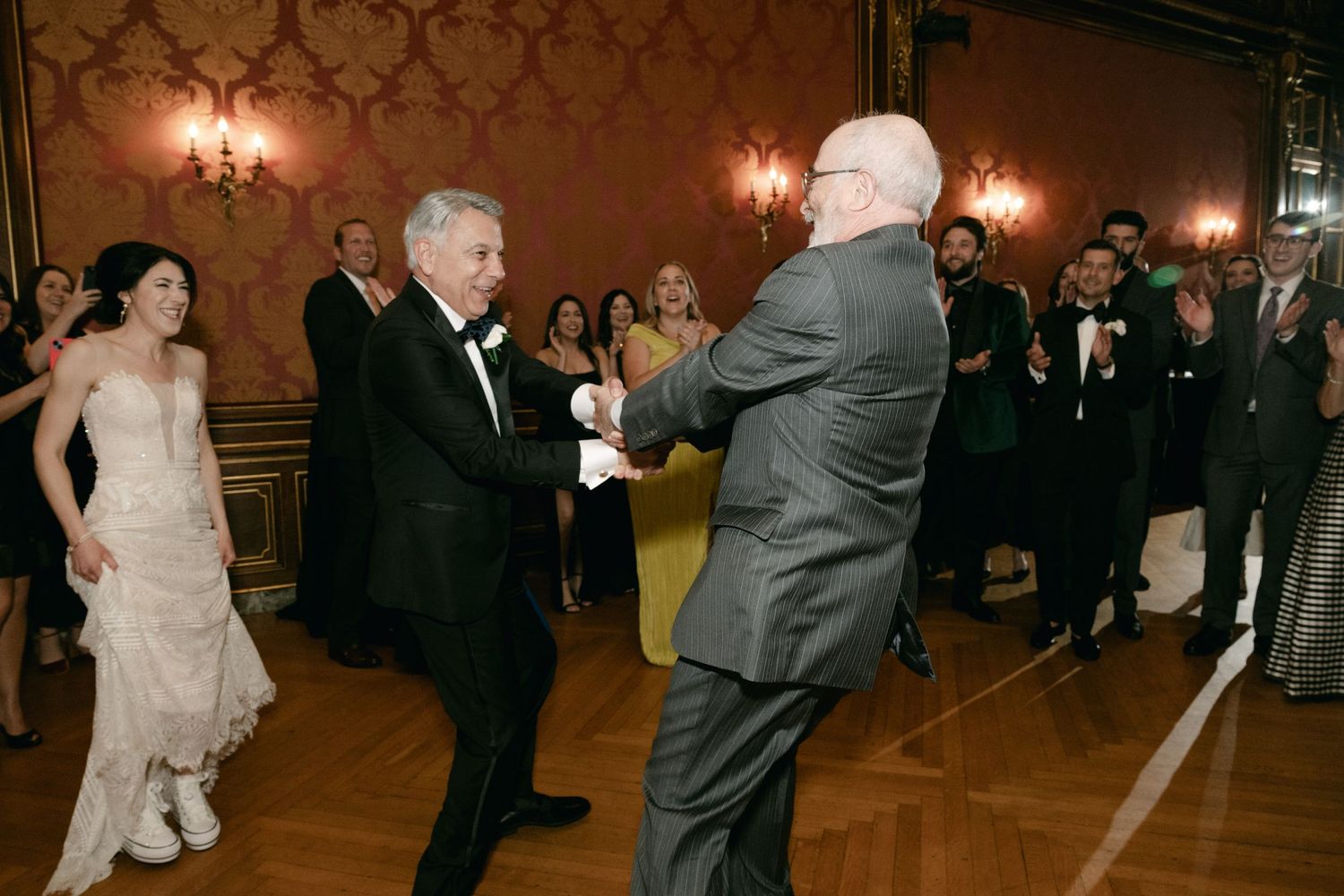Wedding reception dance floor with guests celebrating in a warmly lit ballroom.