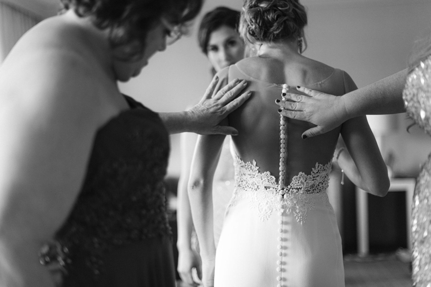 Close-up detail shots of buttons and lace on a white wedding dress.