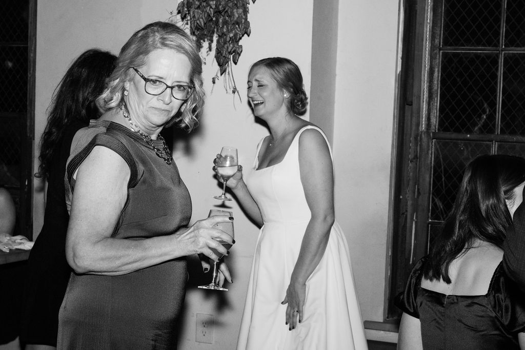 Black and white photo of guests dancing and celebrating at an indoor party.