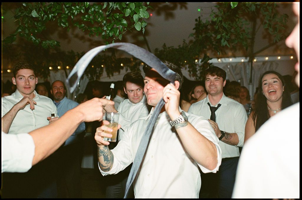 Celebration attendees dance beneath greenery and string lights at an indoor-outdoor venue at Strong Mansion on Sugarloaf Mountain on film
