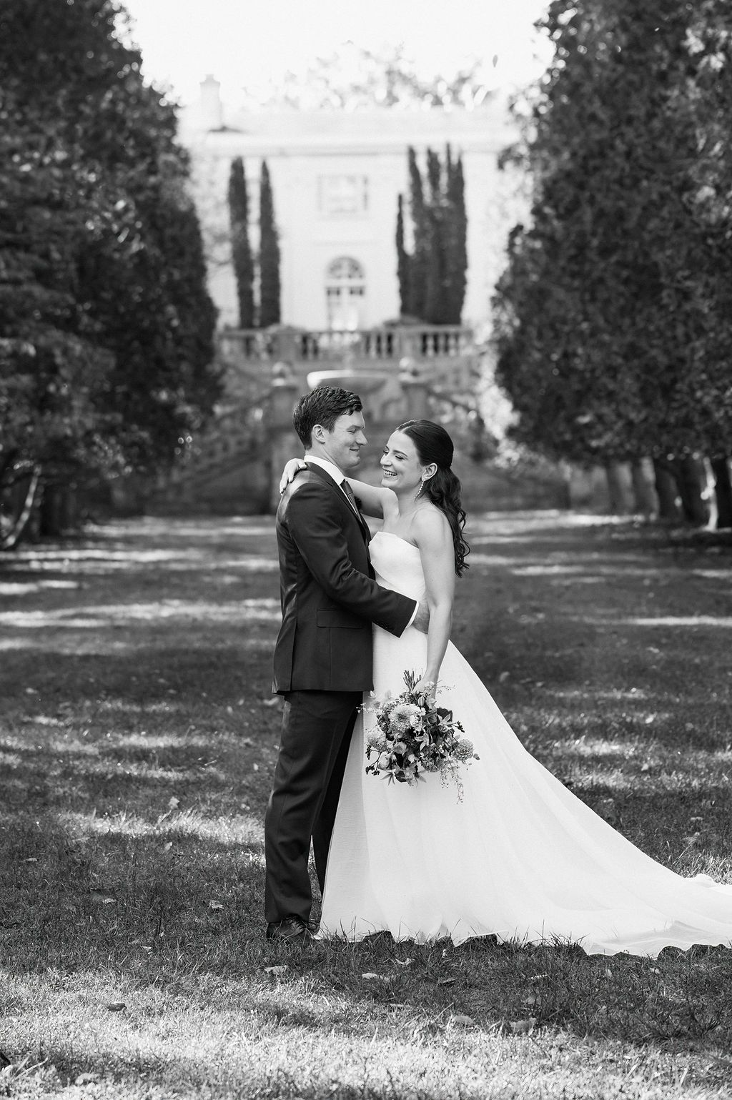 A couple shares an intimate moment on sprawling grounds of an elegant estate.