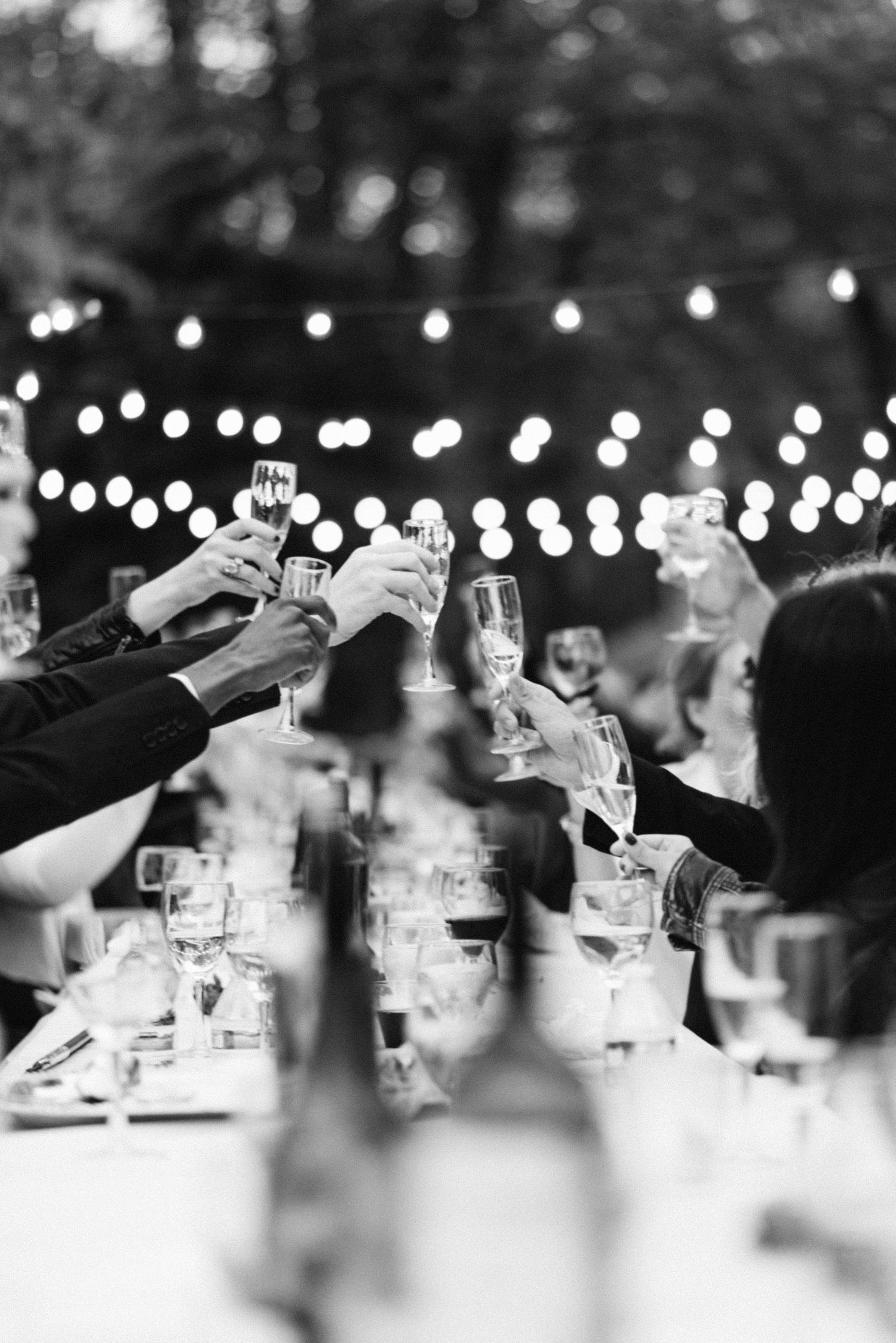 Black and white photo of wedding reception with string lights creating a dreamy atmosphere.