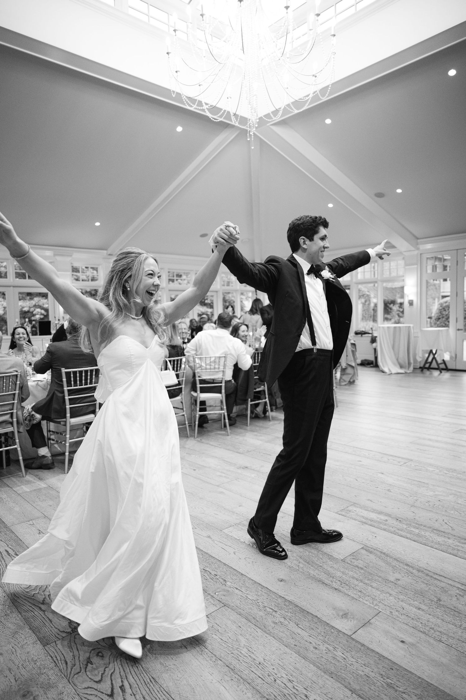 Bride and groom share their first dance at a wedding reception in a bright elegant ballroom.