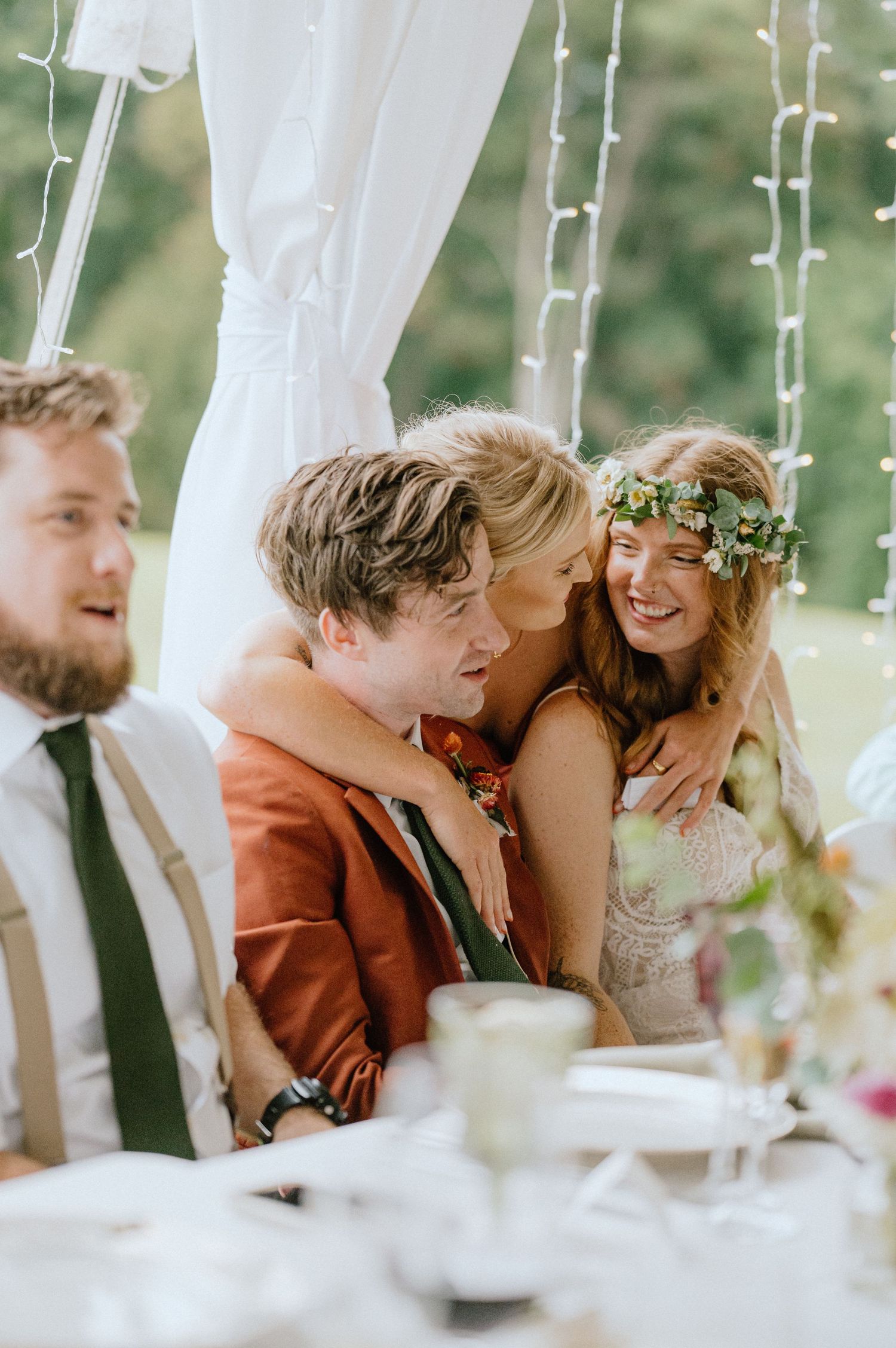 Intimate candid moment between couple under white tent with string lights and floral decor.