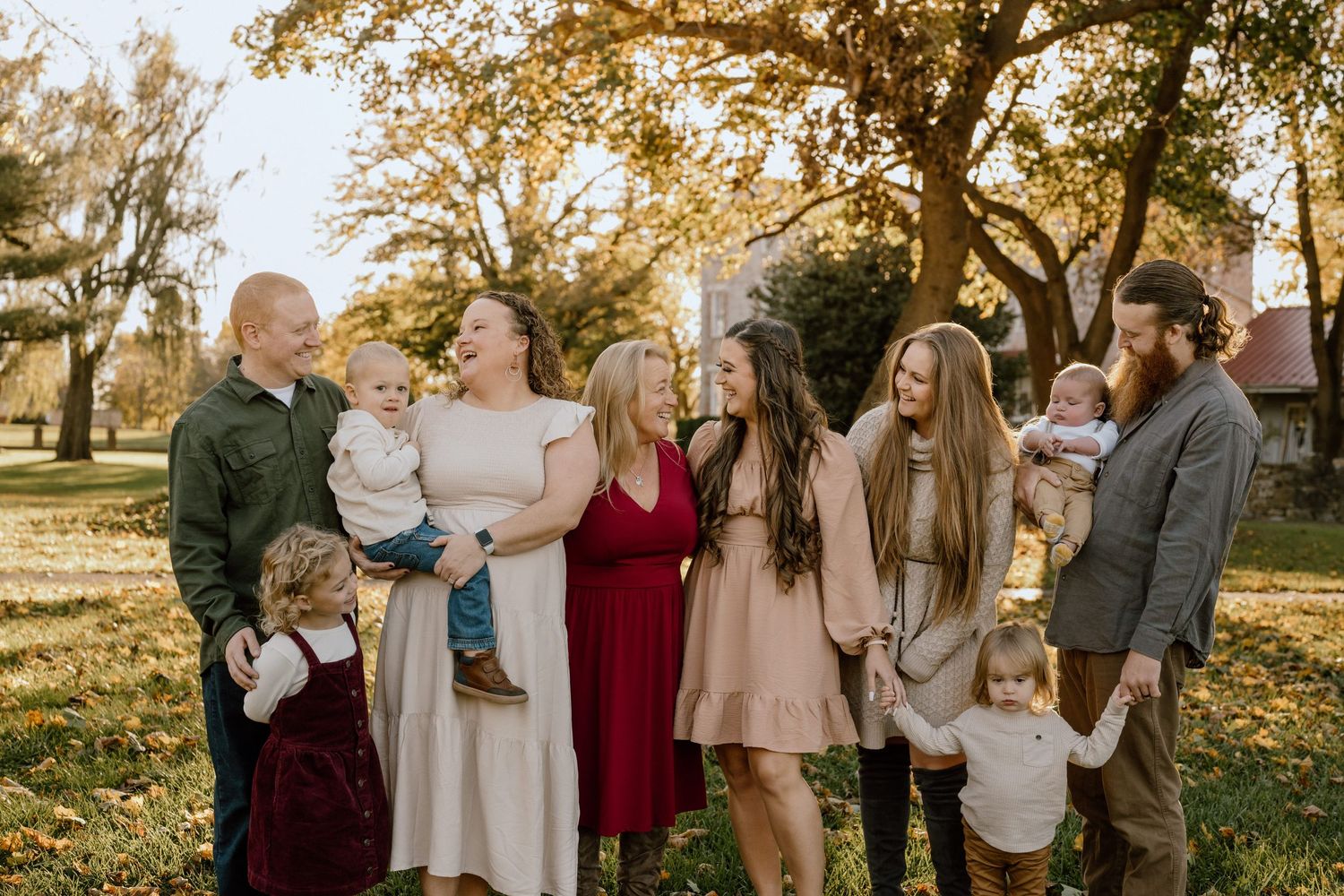Extended family gathering for a portrait in a park setting during autumn.