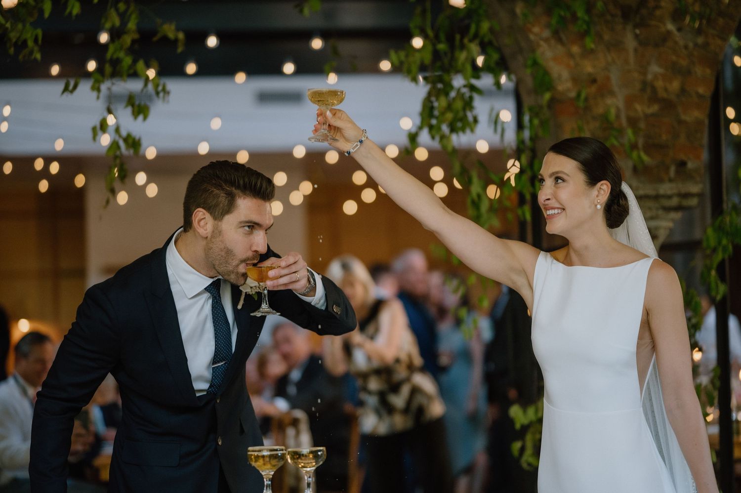 A couple performs an elegant dance move under twinkling lights at their reception.