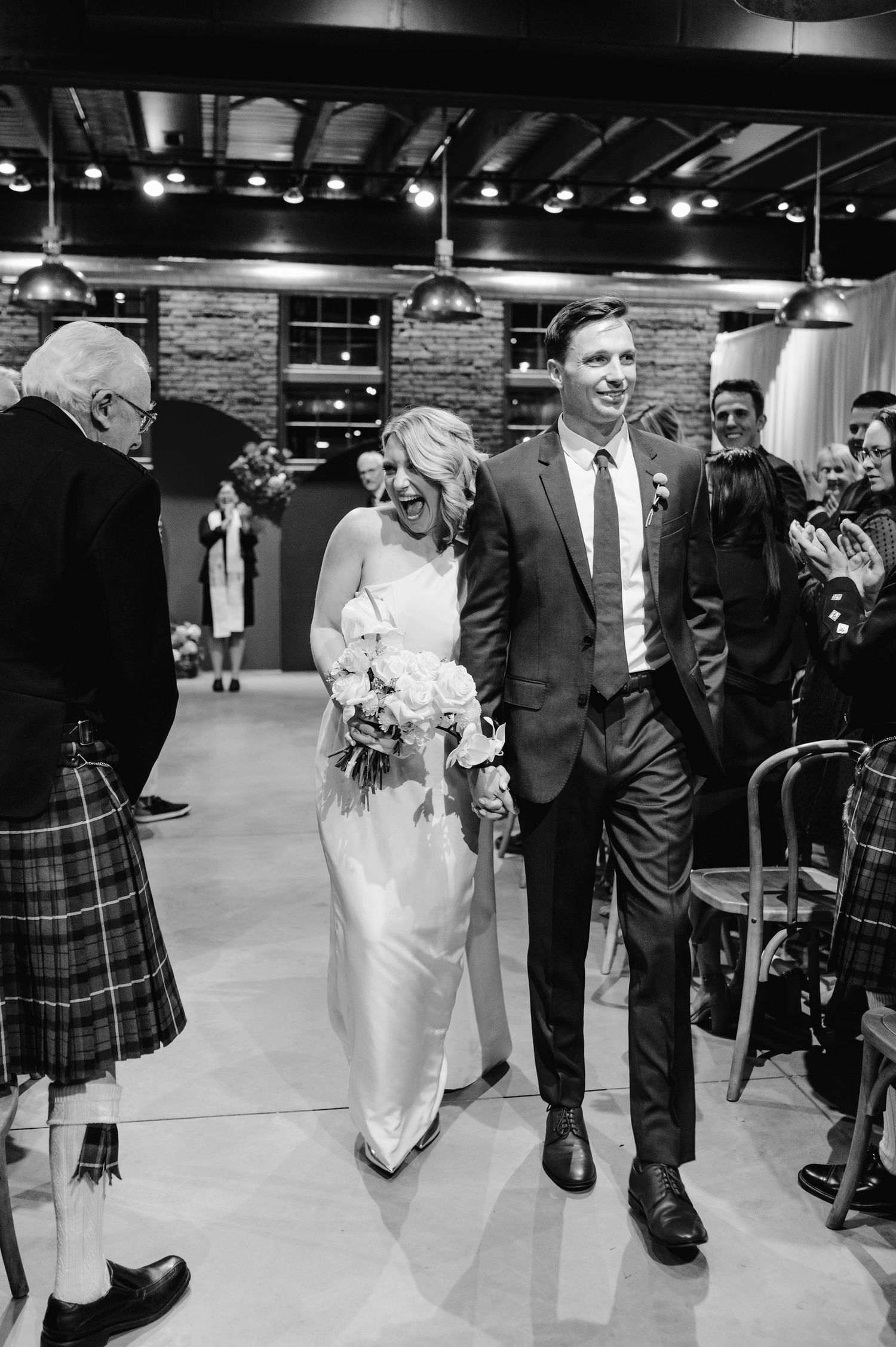 Black and white photo of a wedding exit with guests looking on in an industrial venue.