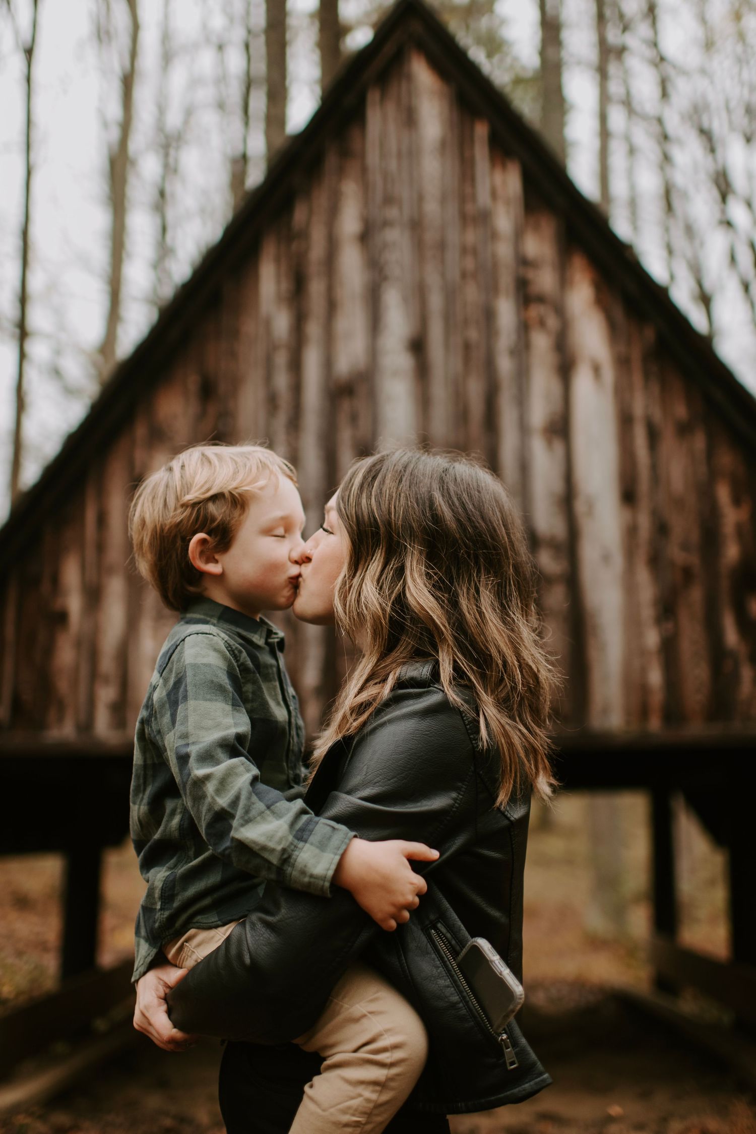 Sweet moment captured in front of rustic wooden building during fall.