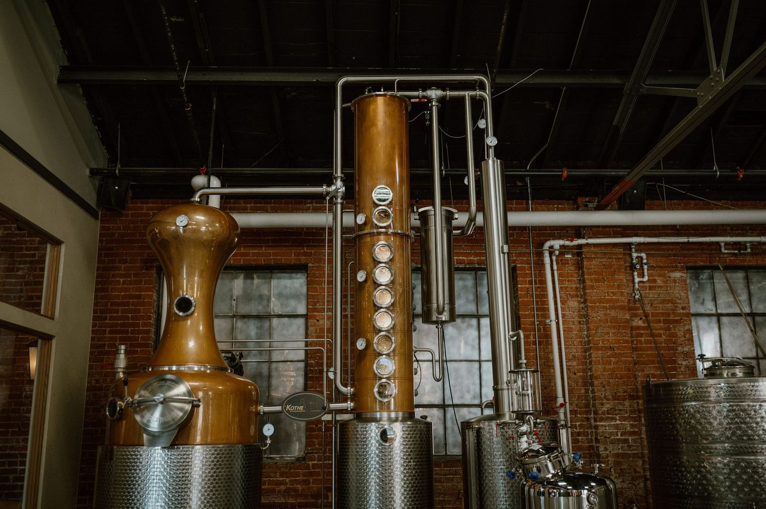 Copper distilling equipment and metal tanks in an industrial spirits manufacturing facility.