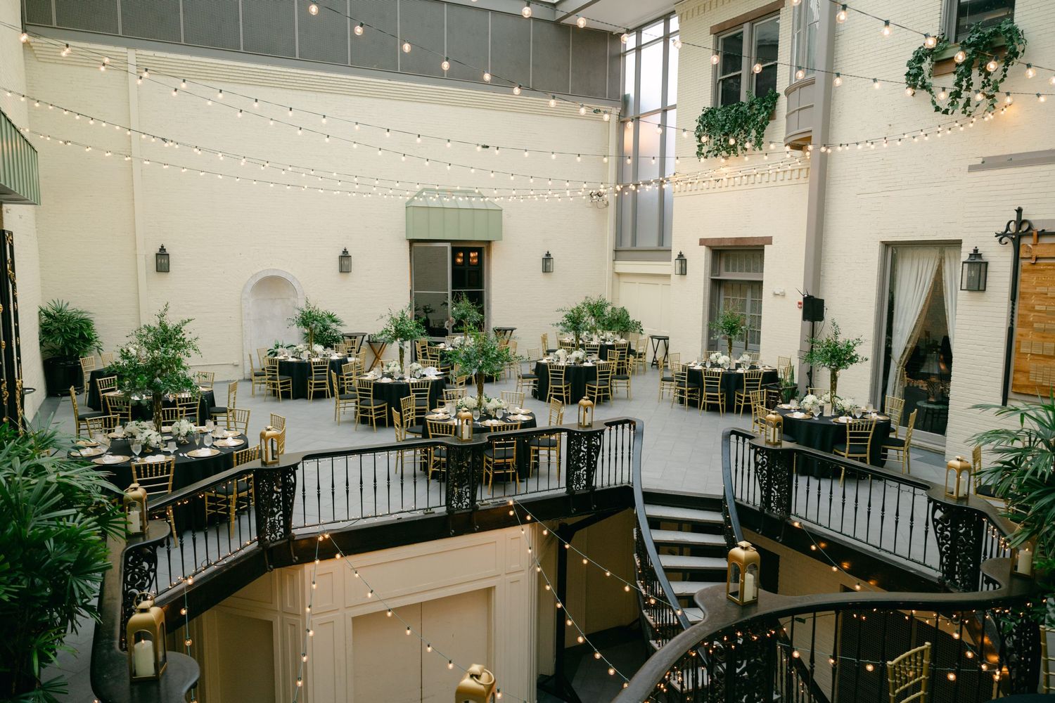 Modern wedding reception venue with elegant table settings and hanging string lights.