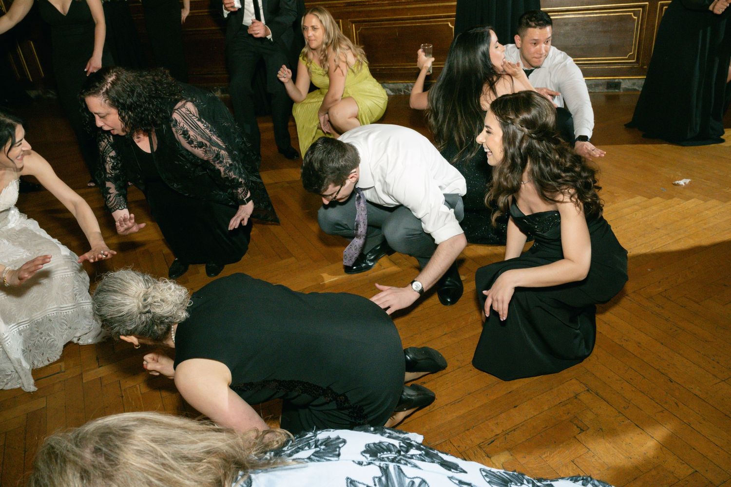 Wedding party members performing a dance routine on a polished wooden floor.