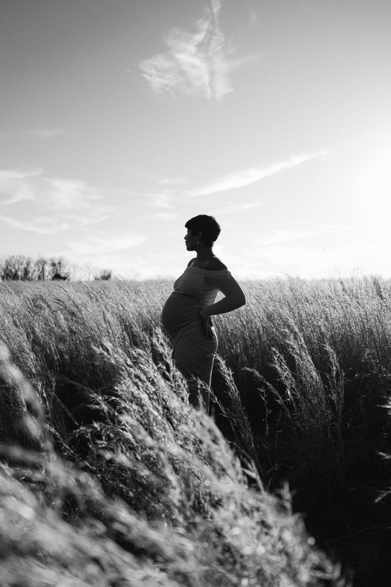 maternity photo of woman holding baby bump in field