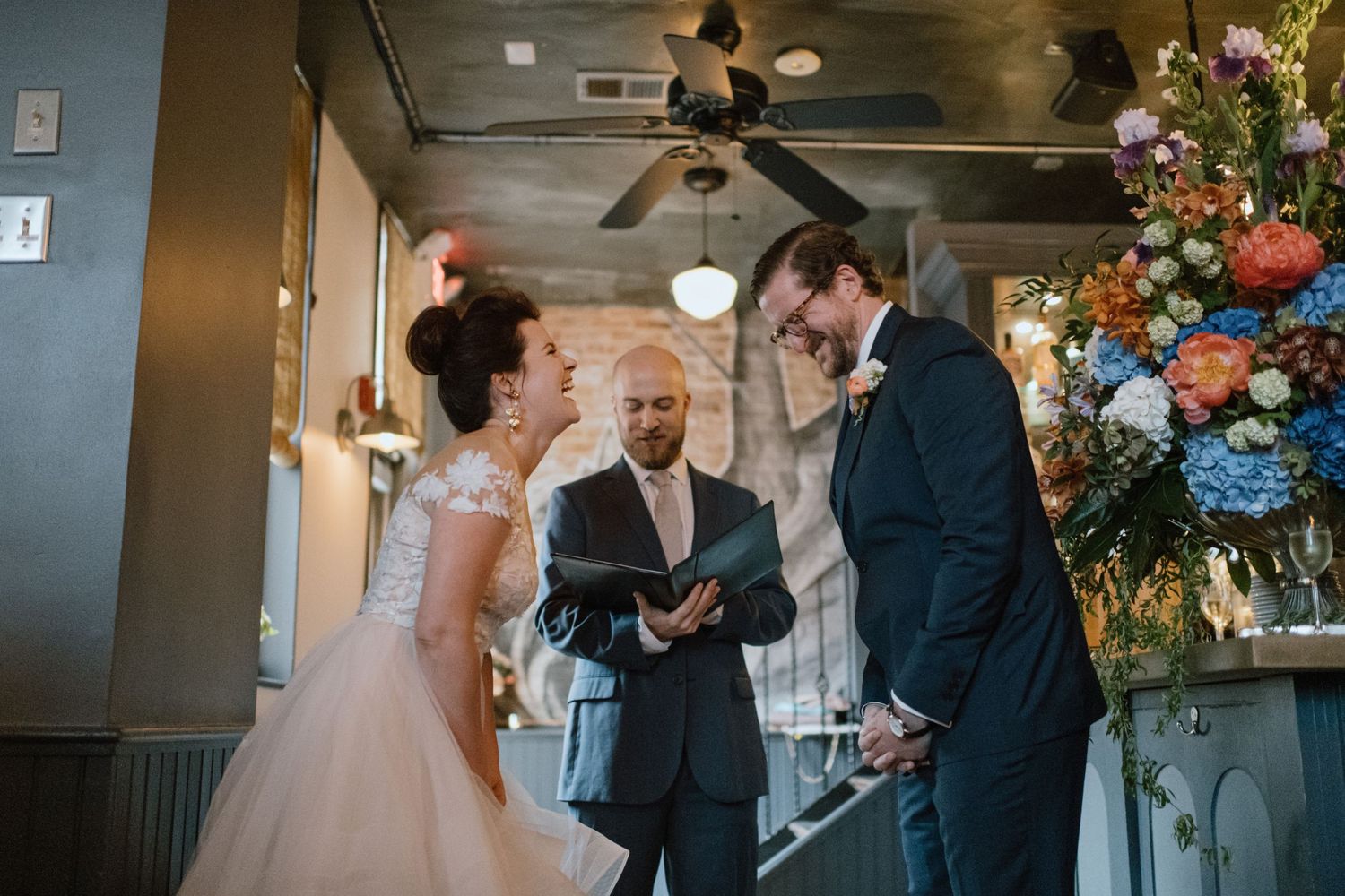 An intimate wedding ceremony with beautiful floral arrangements in an industrial-style indoor space.