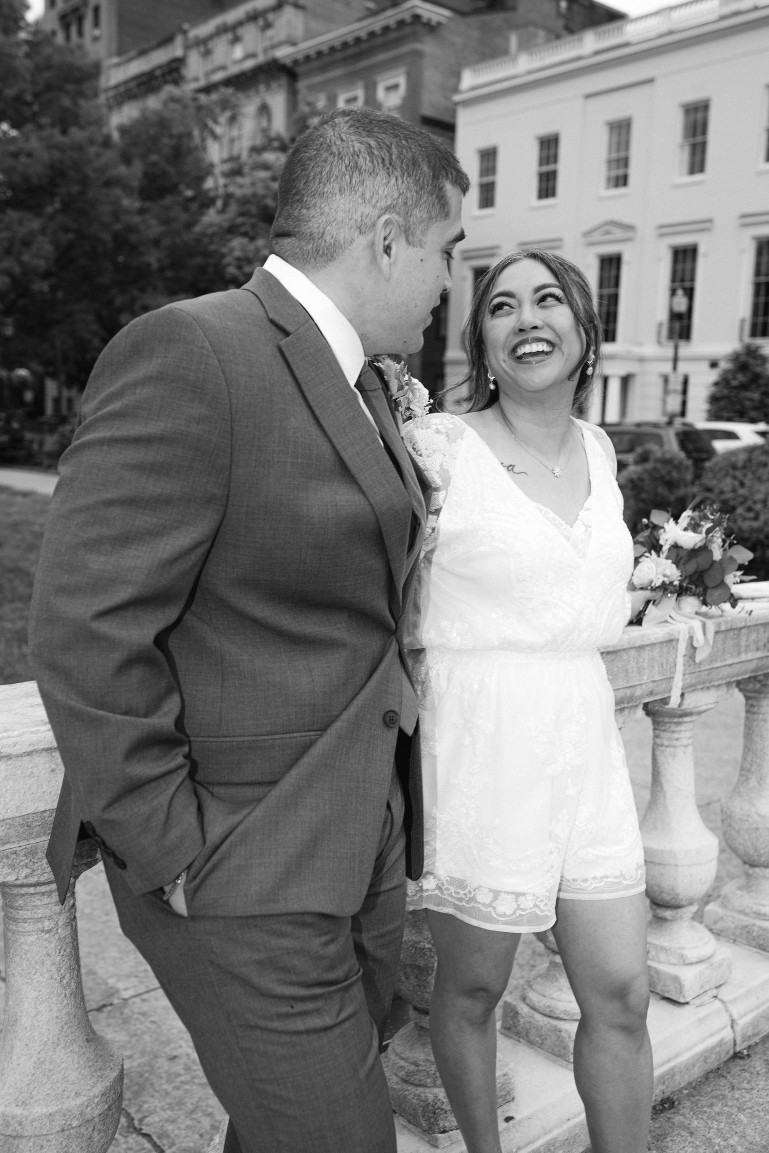 A romantic moment captured on an elegant stone balcony in black and white.