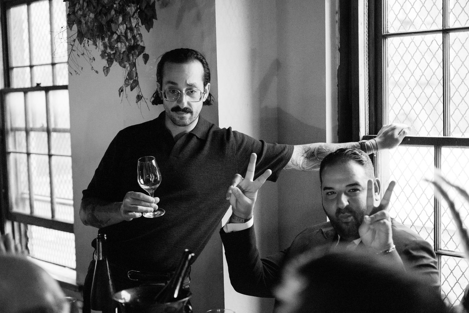 Two people enjoying drinks and conversation in a window-lit room at Fadensonnen in Baltimore