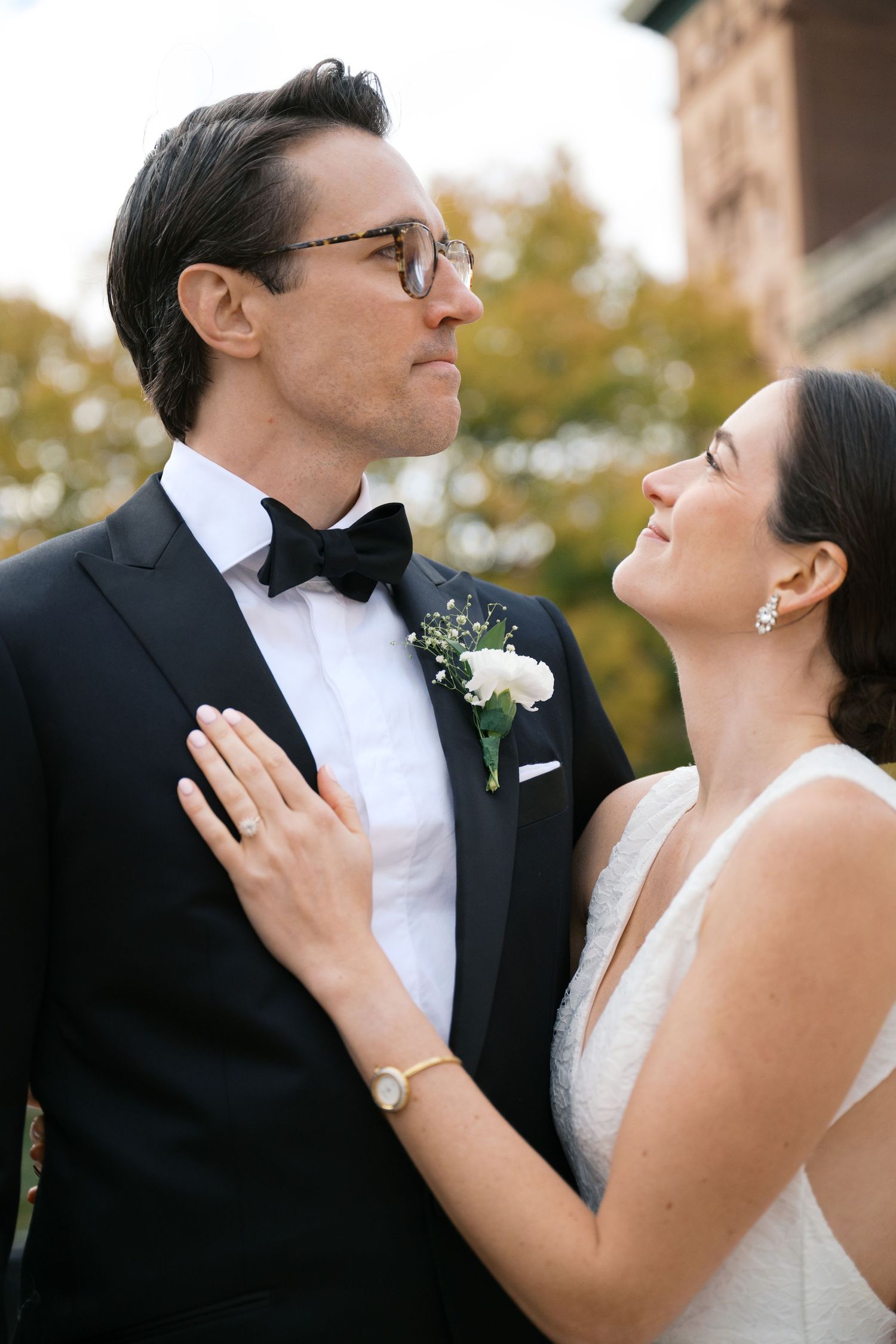 Intimate wedding portrait captured outdoors with fall foliage in background.