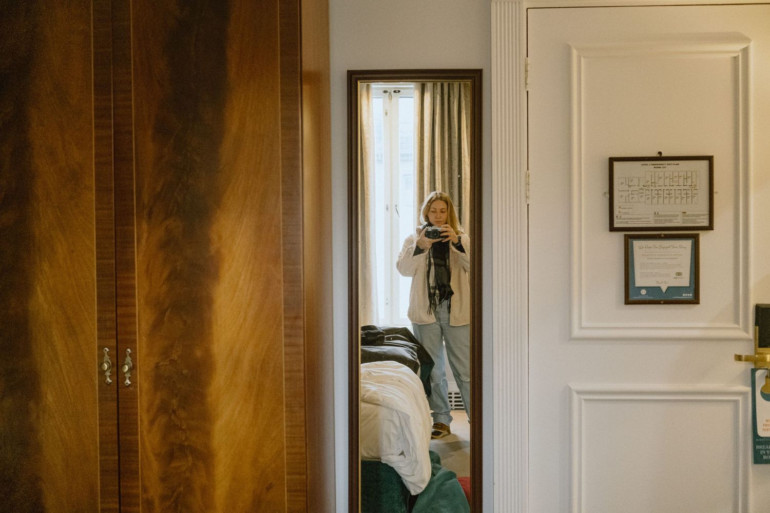 View through doorways into a bright hotel room with vintage furnishings.