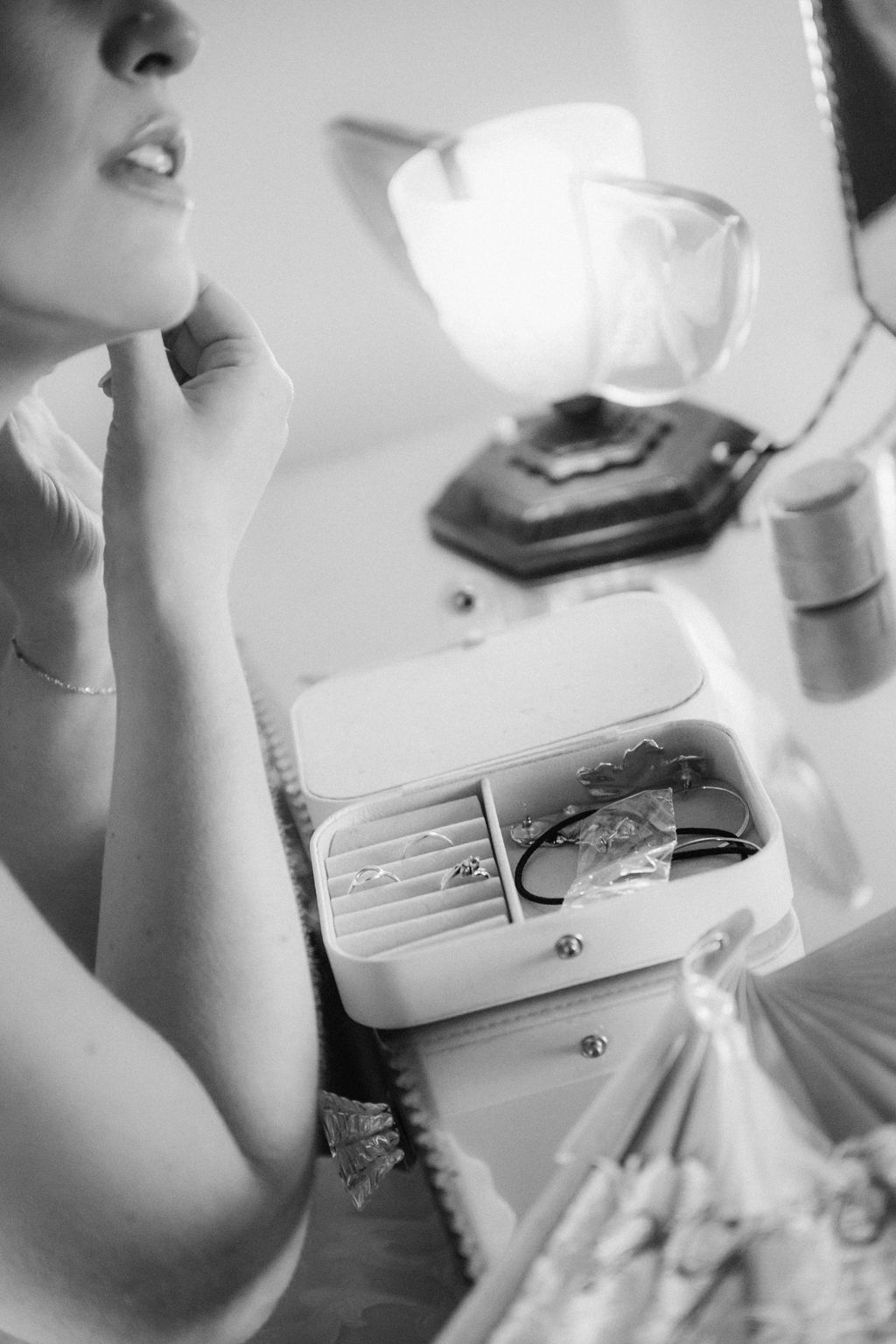 Black and white photos showing hands holding and opening a small white purse or clutch bag.