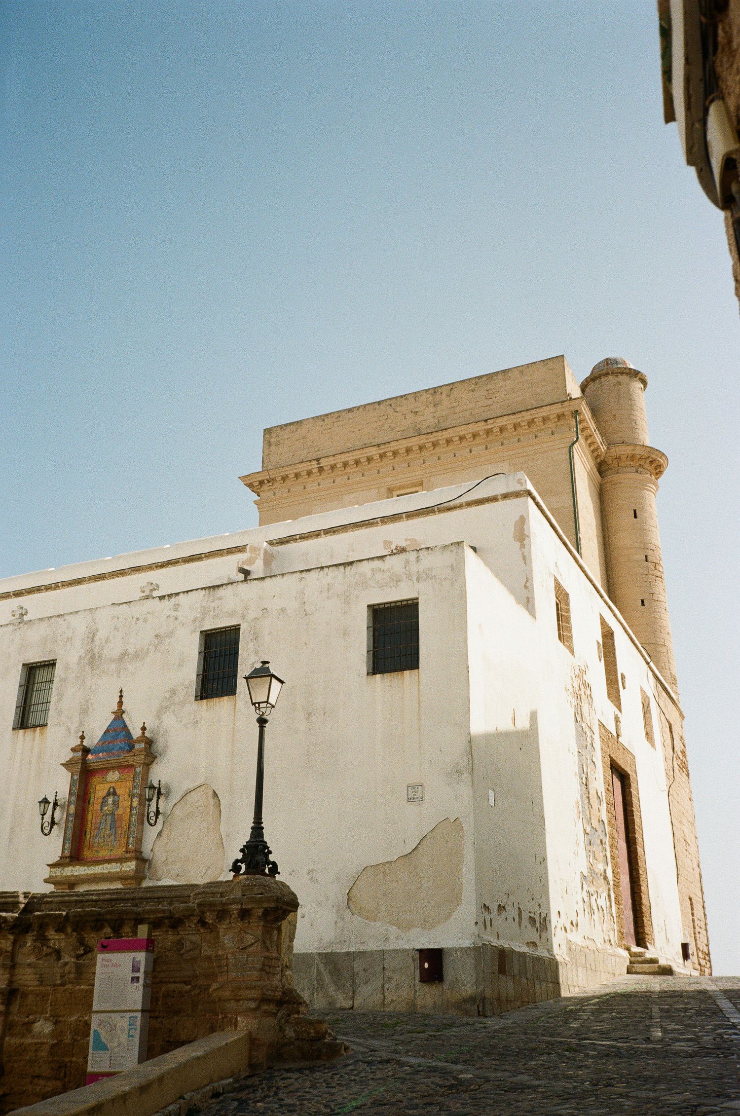 Historic white building with ornate architectural details and a small tower in a Mediterranean coastal town.