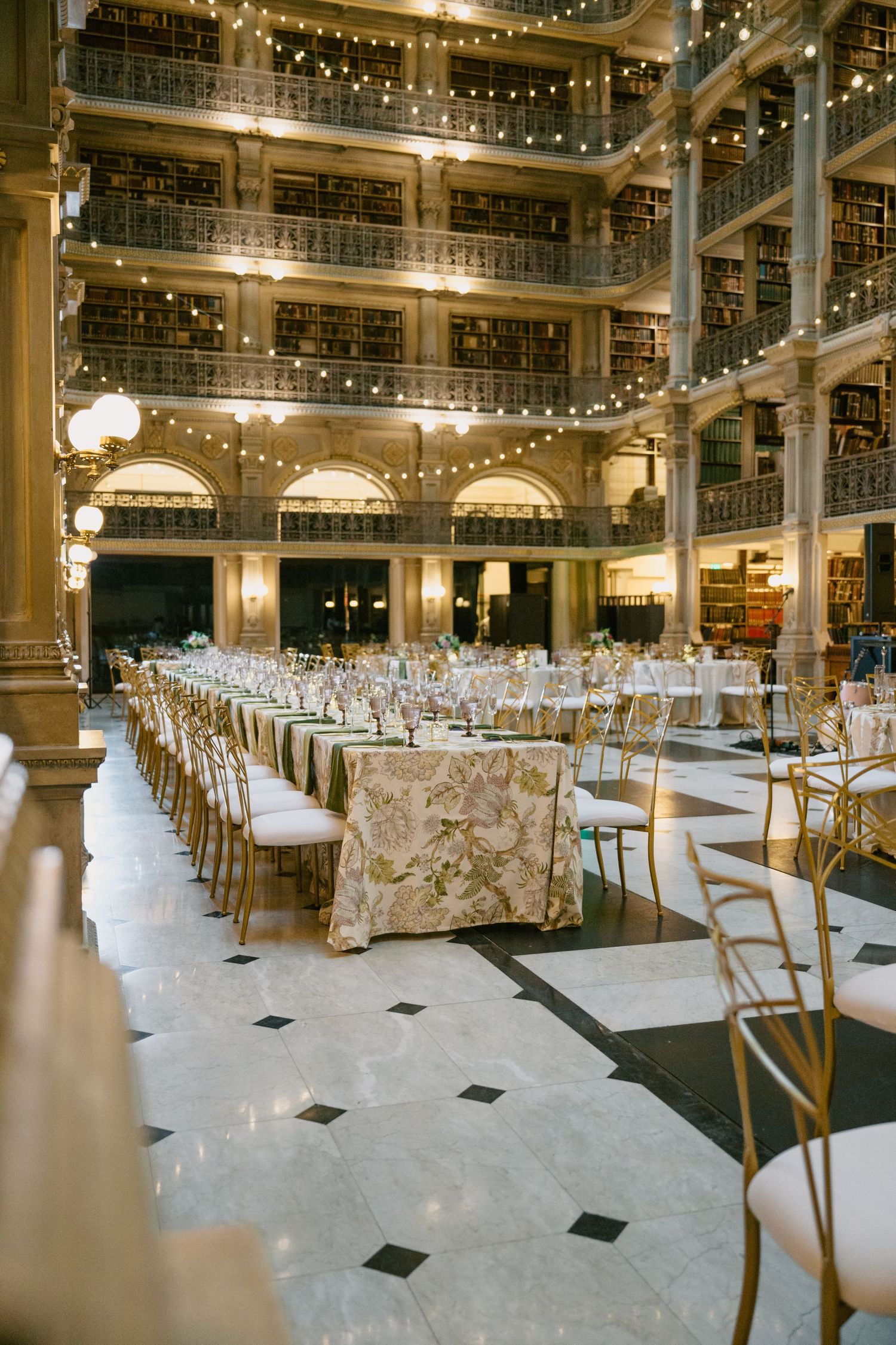 Grand library space set up for wedding reception with elegant table settings and string lights.