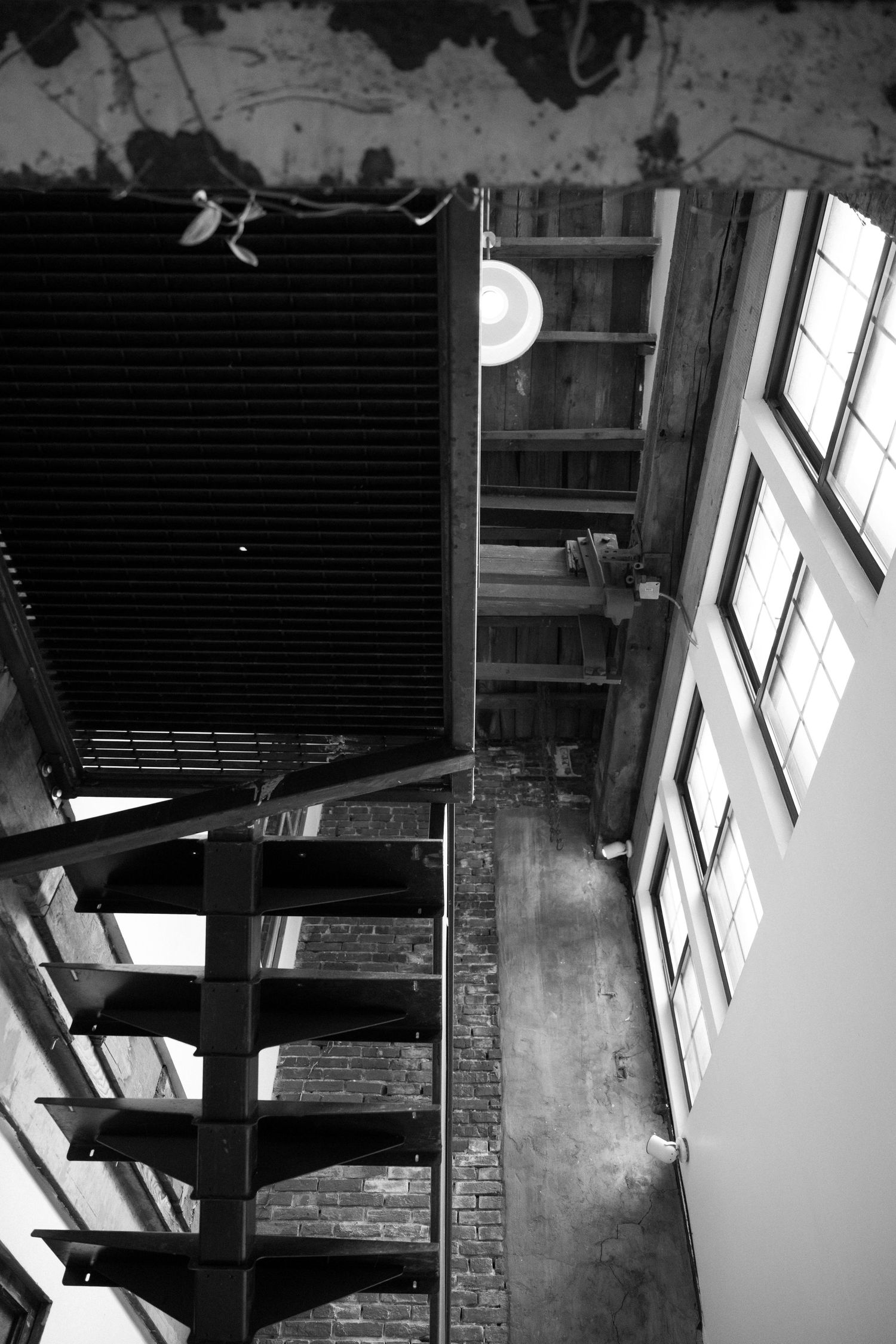 High-contrast black and white interior view showing exposed wooden beams, windows, and architectural details.