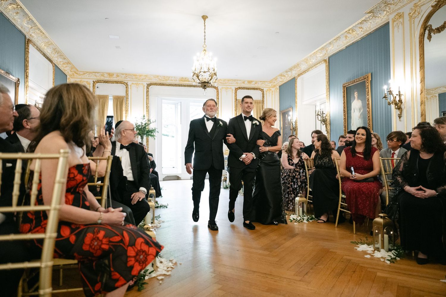 Wedding ceremony in an elegant blue room with crown molding and crystal chandeliers.