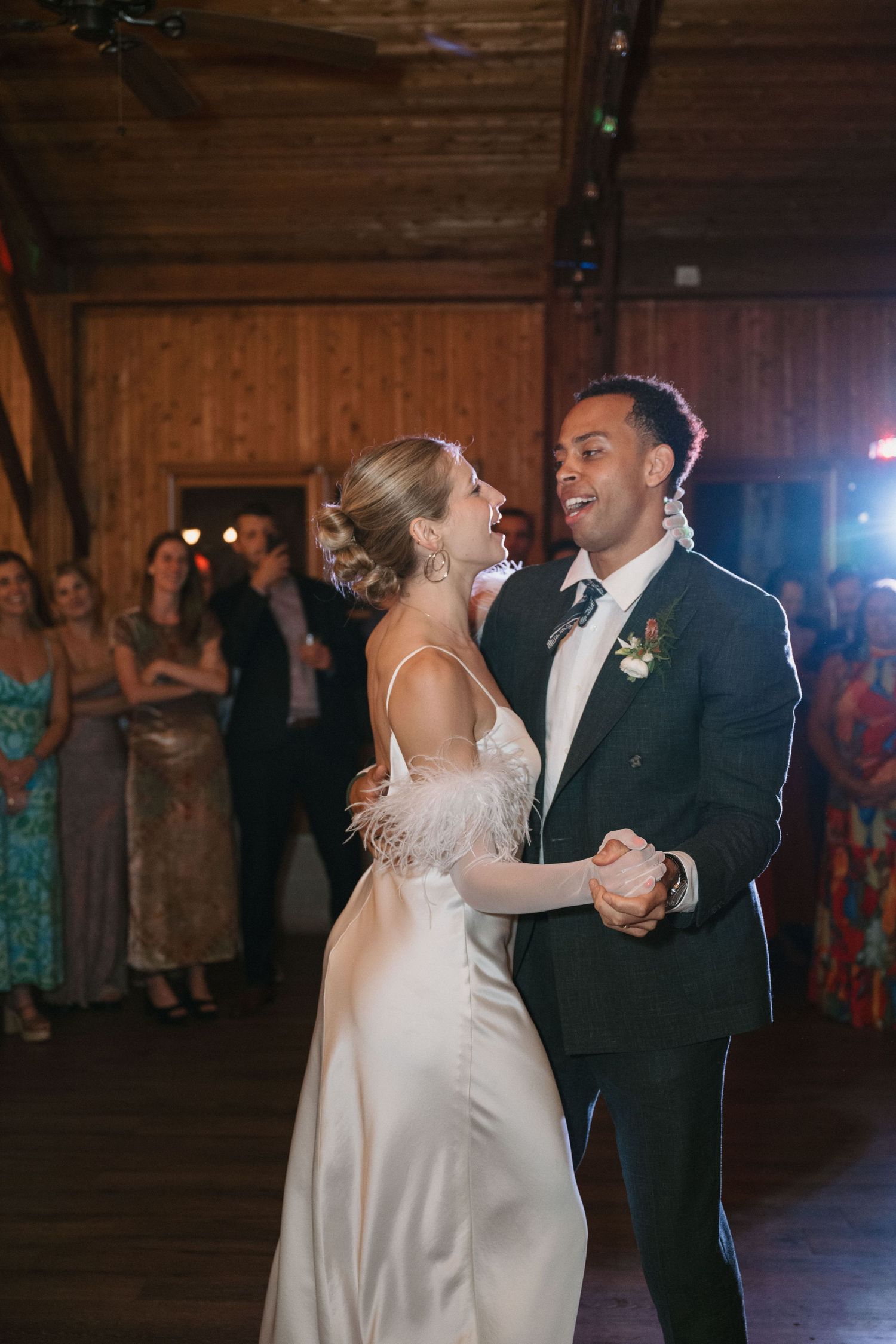 Couple sharing their first dance in rustic barn venue with wooden walls and romantic lighting.