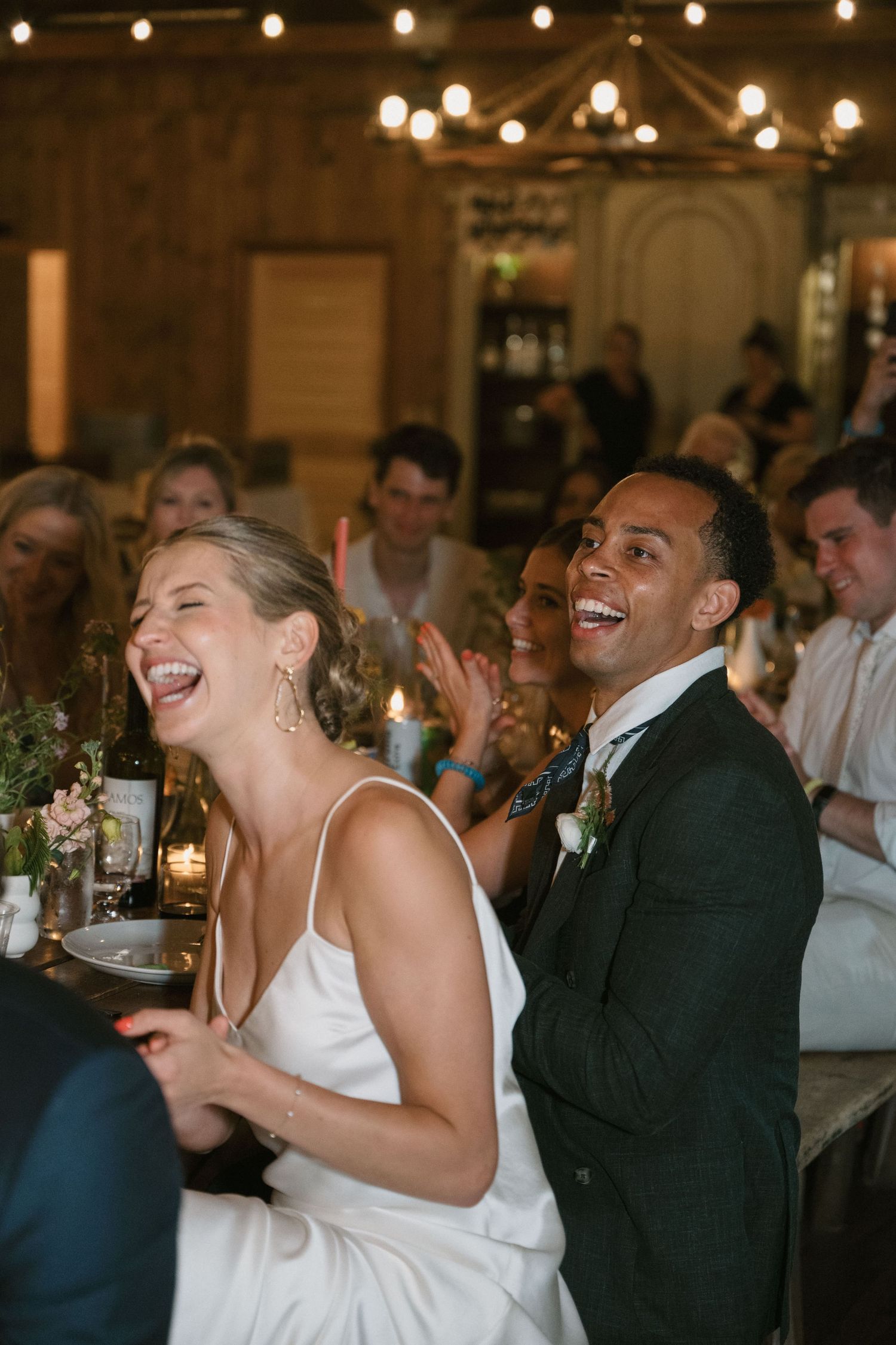 Candid moment of shared laughter during wedding reception celebrations.