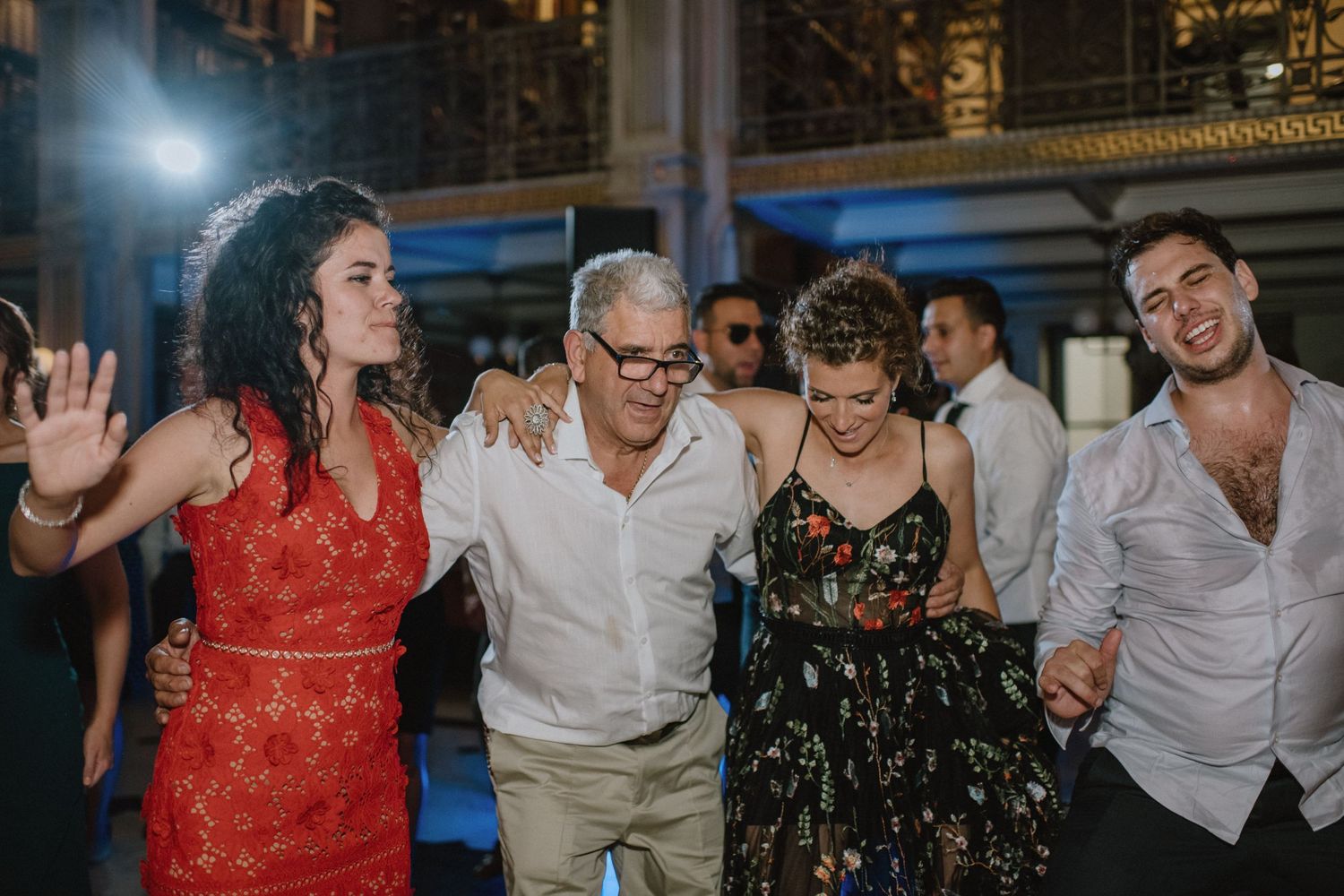 Wedding guests dance and celebrate together on the dance floor in colorful attire.