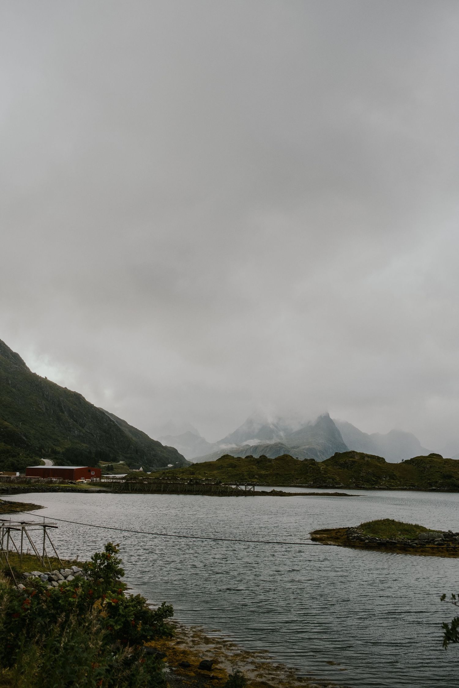 Misty mountain landscape with calm fjord waters and distant peaks.