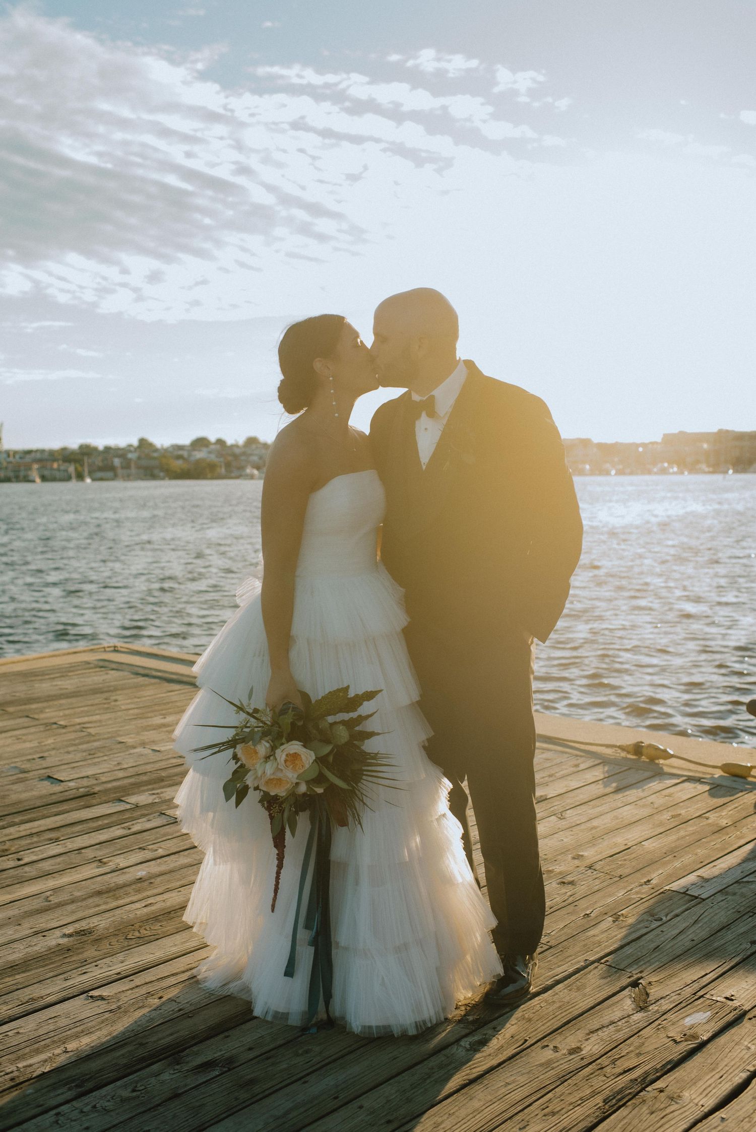 A romantic silhouette of newlyweds sharing a moment on a dock during golden hour.