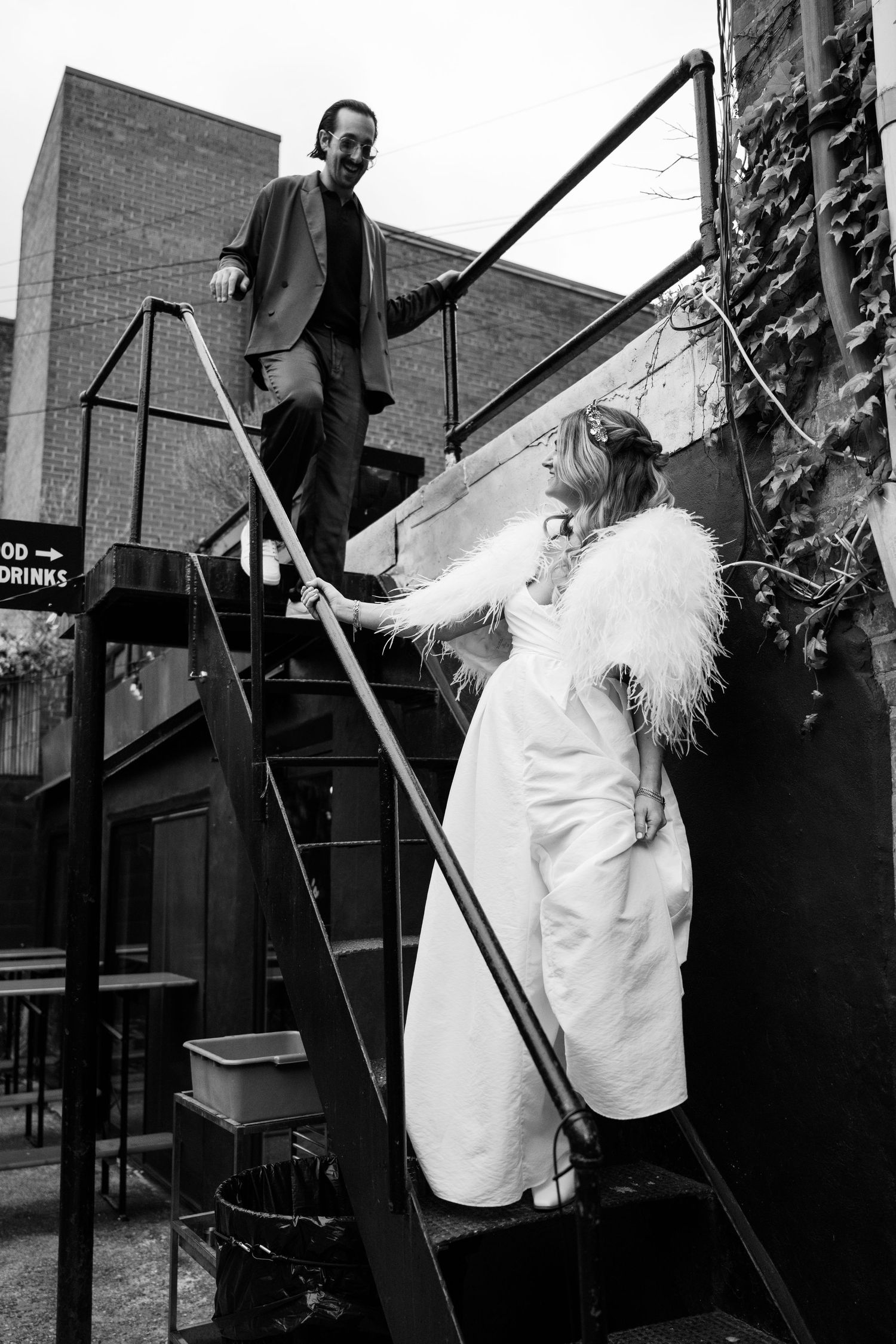 A couple on an outdoor staircase with the bride wearing a feathered white dress at Fadensonnen in Baltimore