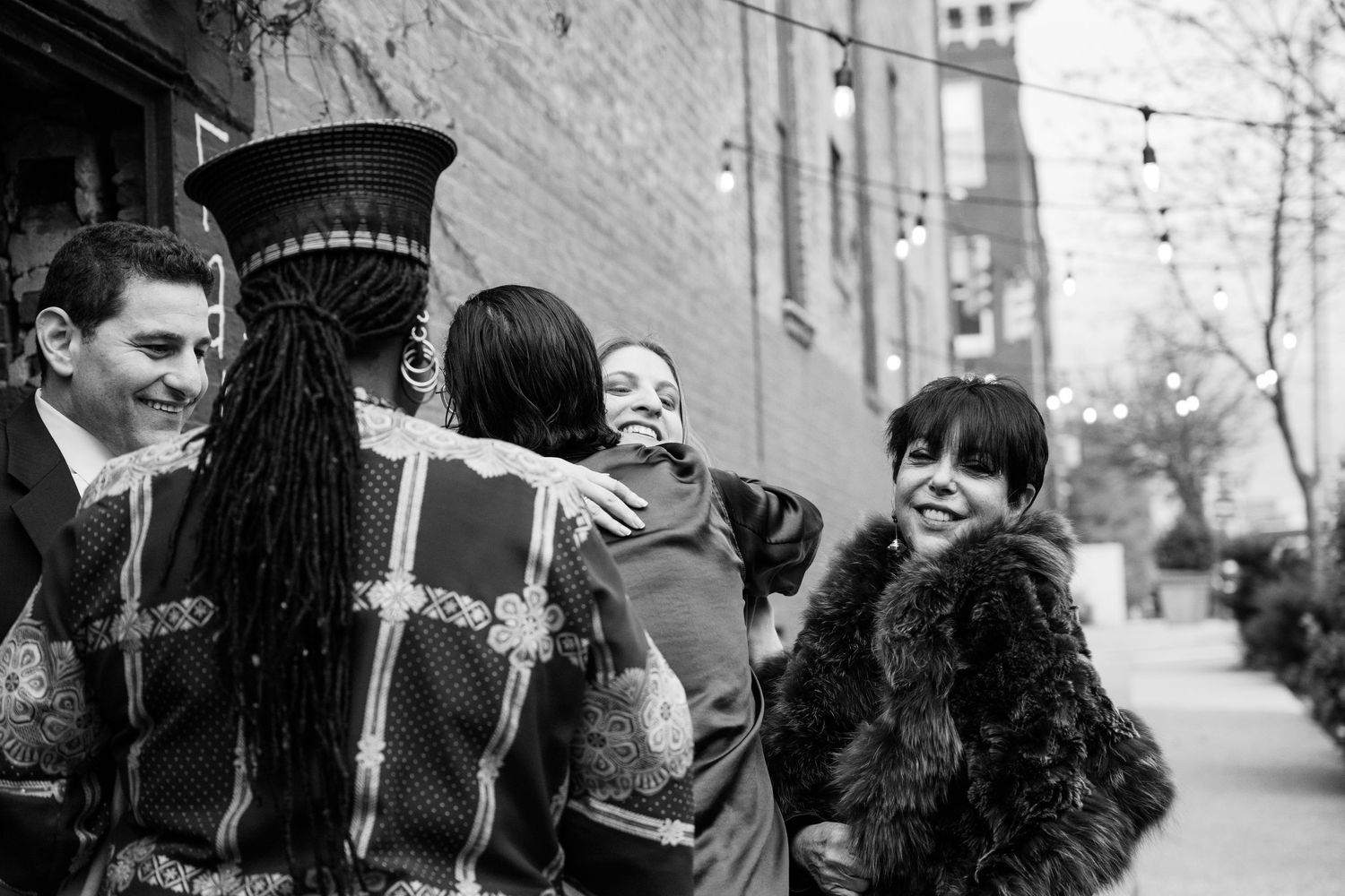 A group of people laughing together on a city sidewalk during what appears to be a celebration.