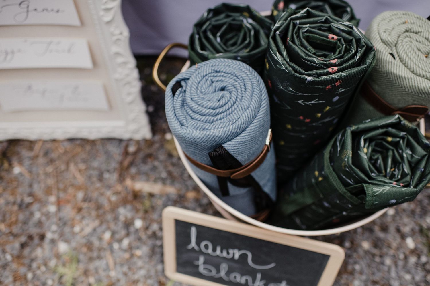 Rolled up blankets or textiles in green and blue tones displayed near a small chalkboard sign.
