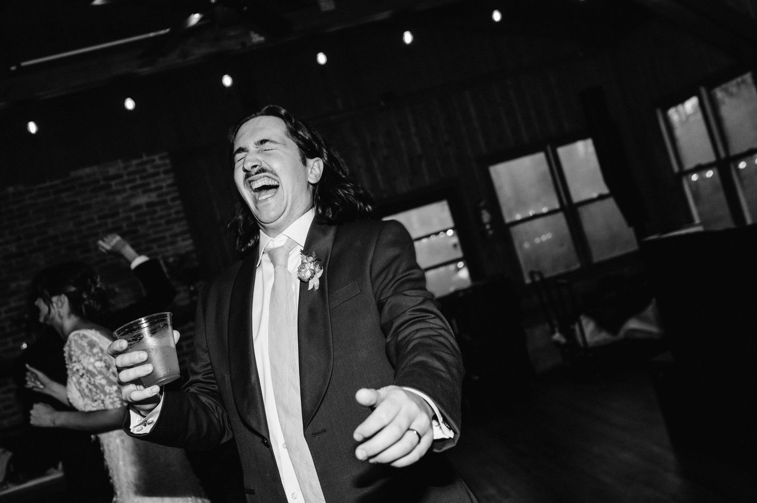 Black and white photo of a guest dancing enthusiastically at a wedding reception.