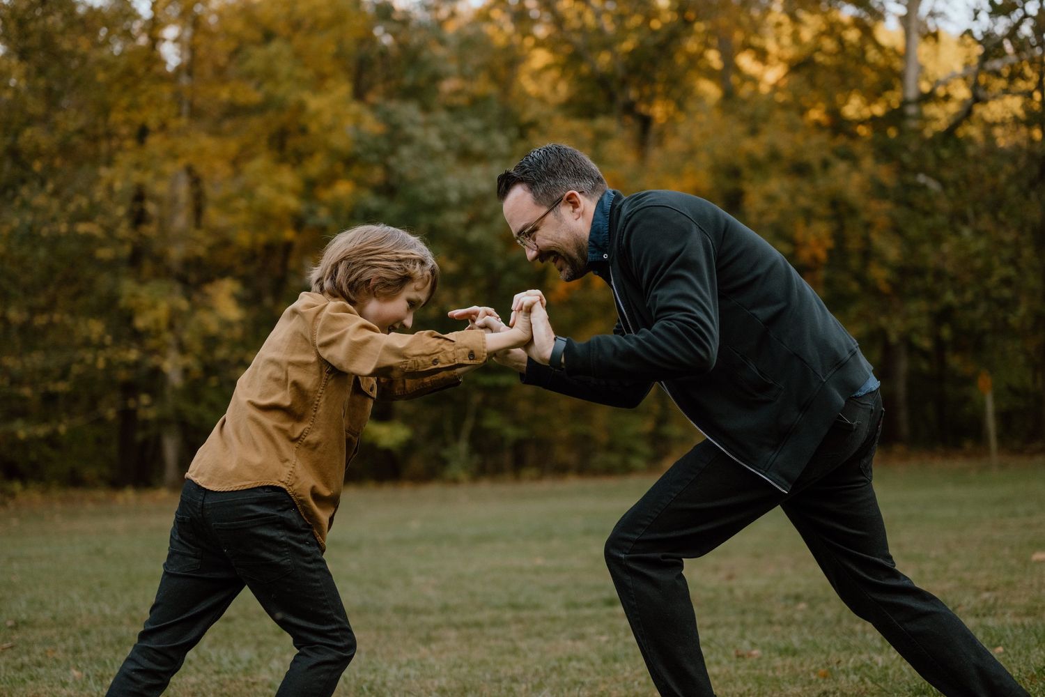 Playful scene of two people mock-fighting in a grassy field during autumn.